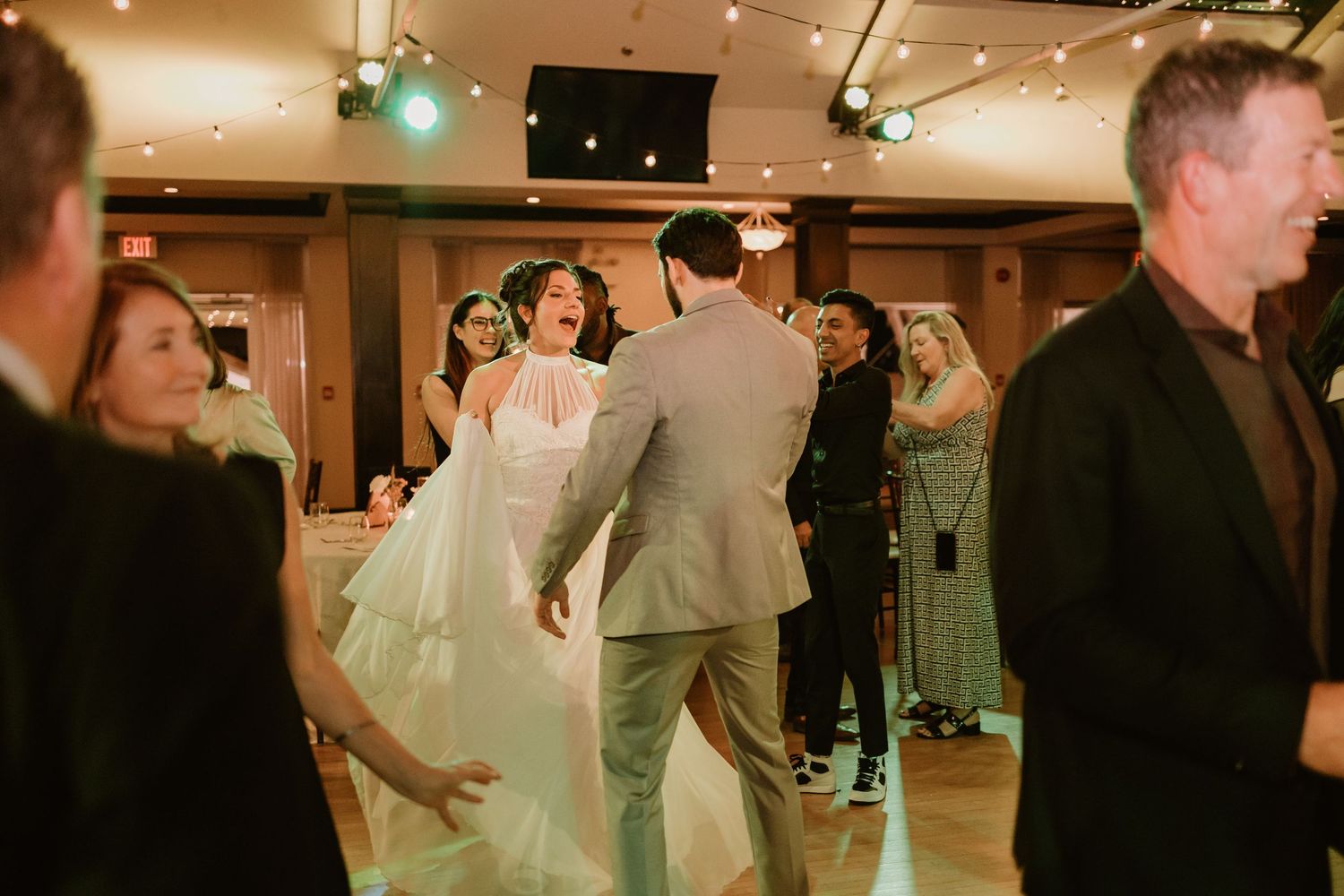 Wedding celebration with guests dancing under warm ambient lighting.