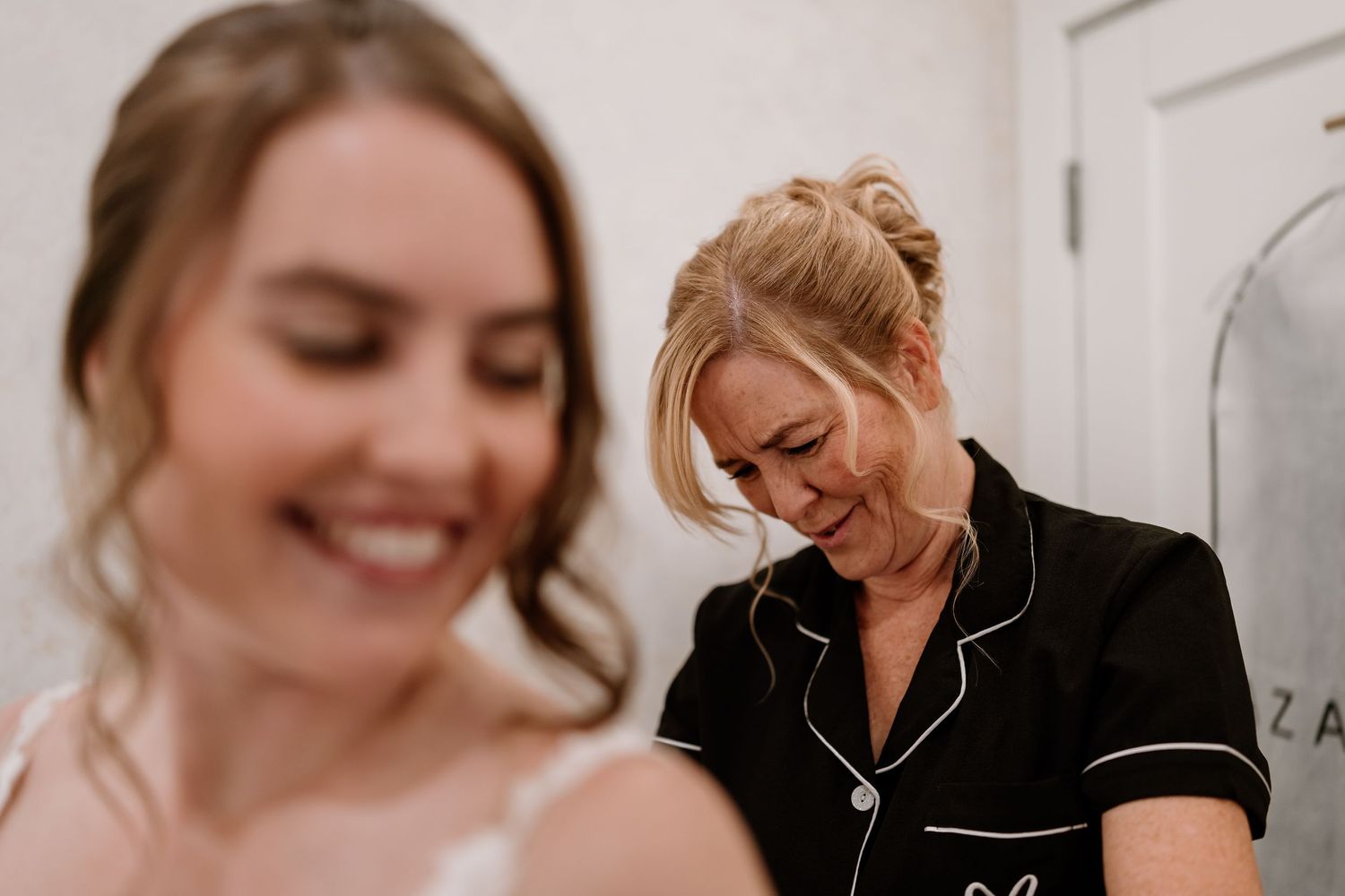 Joyful moments during a wedding dress fitting session in a white room.