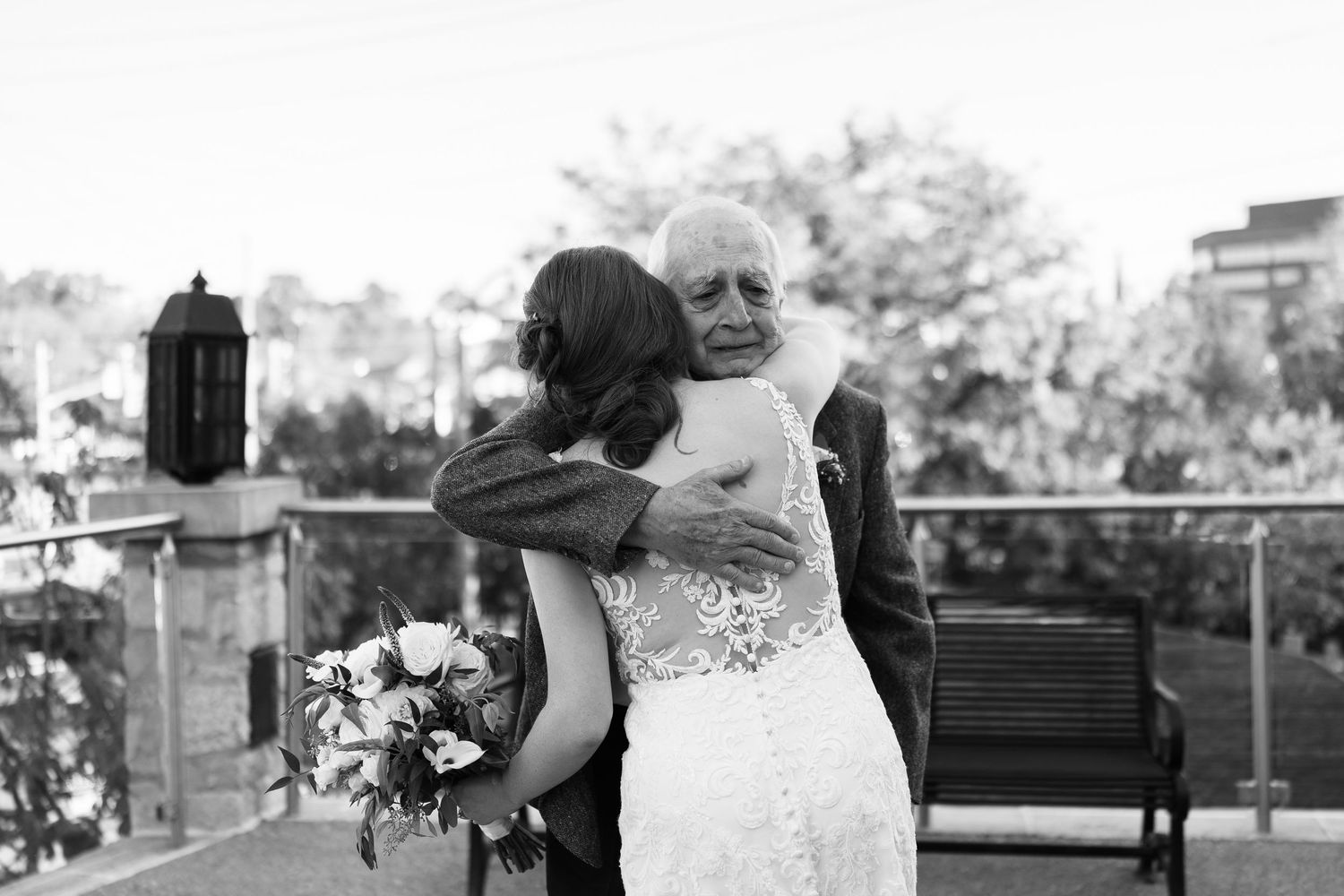 Black and white photo captures emotional wedding moment between two people embracing.