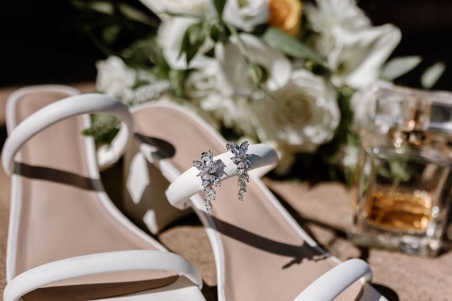Elegant wedding shoes and floral arrangements displayed on a rustic wooden surface.