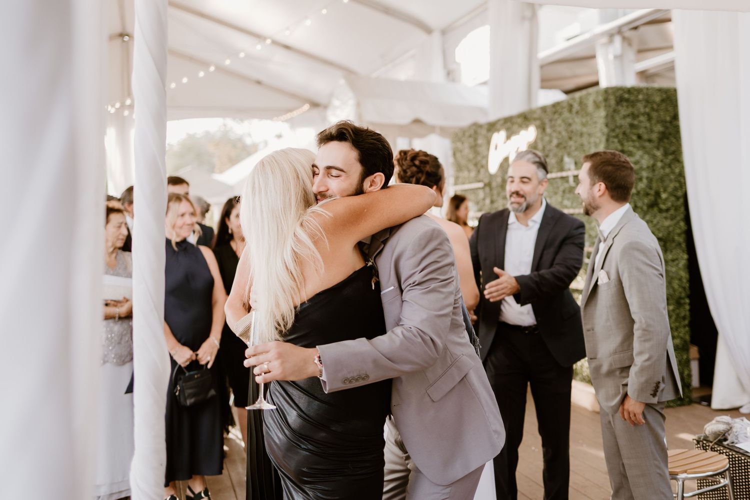 Wedding reception party with guests dancing and celebrating under white tent decorations.