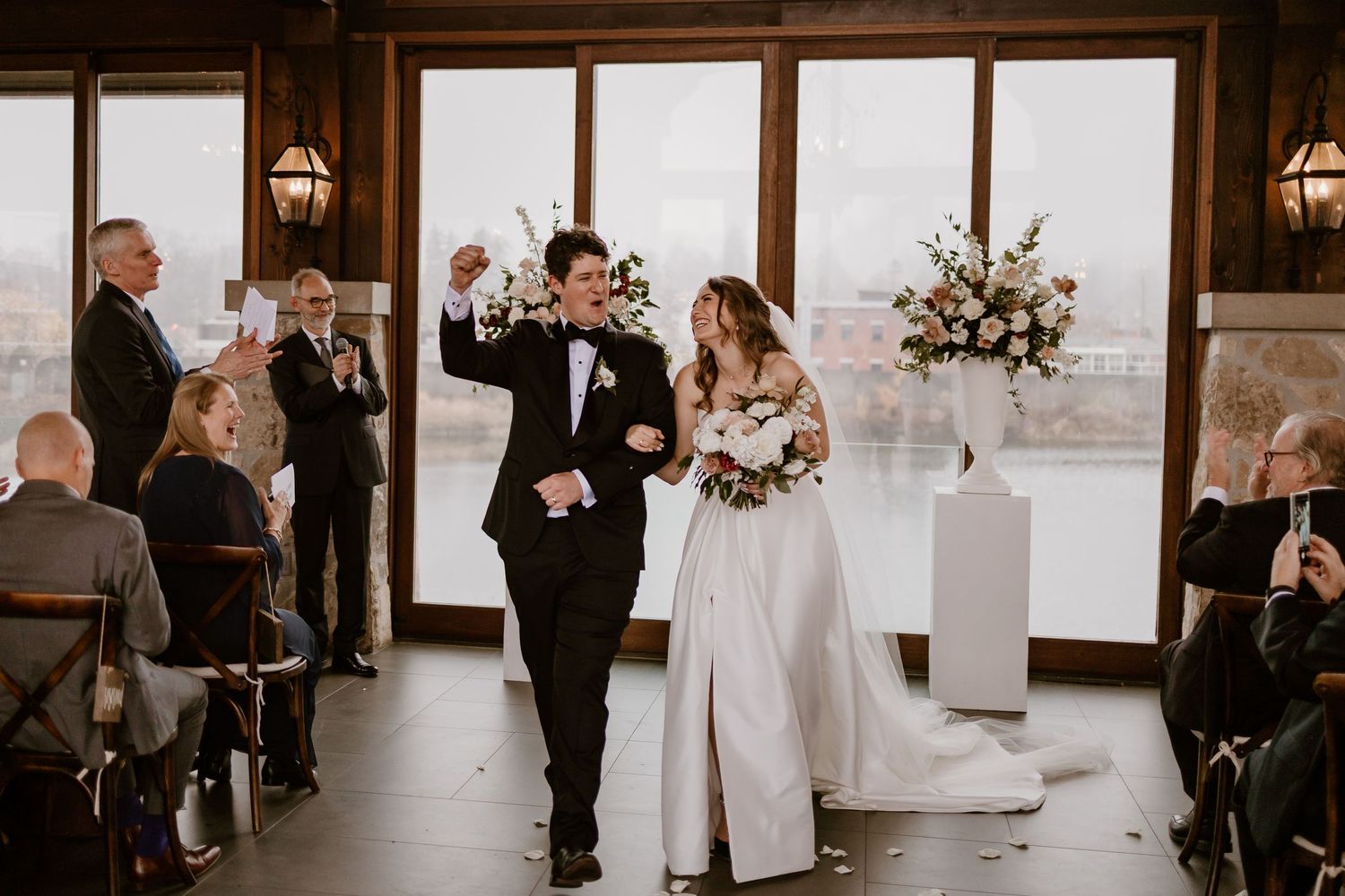 Wedding ceremony in a rustic venue with large windows and natural lighting.