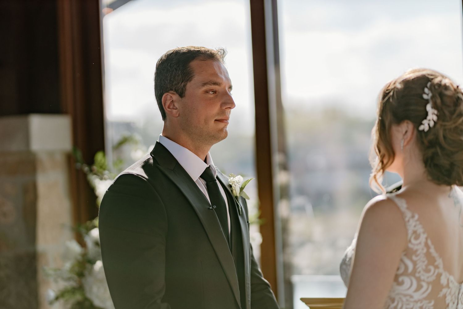 Close-up of wedding ceremony with elegant decor and natural lighting from large windows.