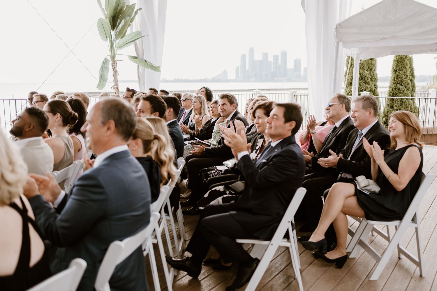 Wedding guests seated in rows at an elegant waterfront ceremony venue.