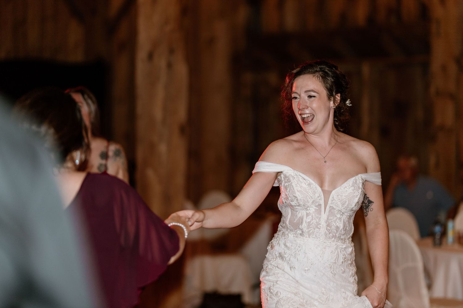 Joyful wedding reception moment in a rustic barn setting.