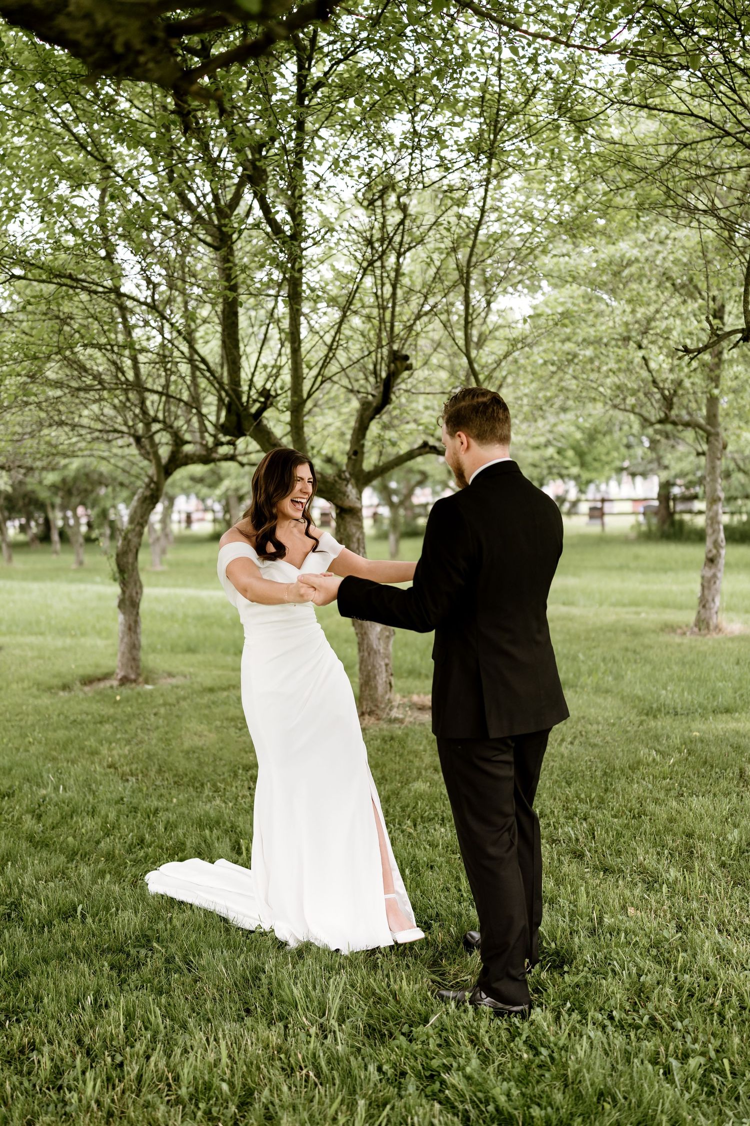 Couple shares romantic dance moves in sunlit orchard setting.