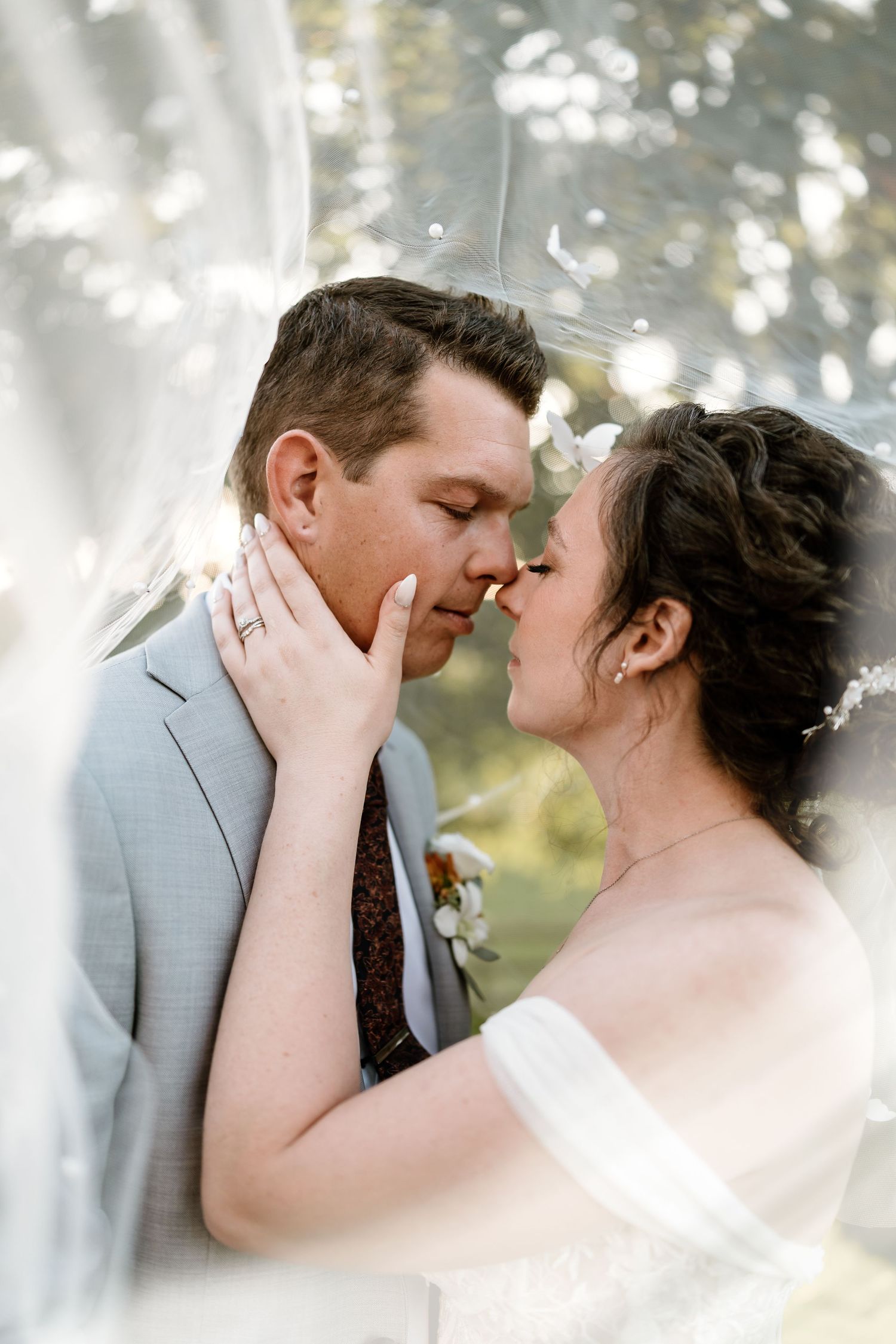 Intimate wedding portrait captured in soft, dreamy lighting outdoors.