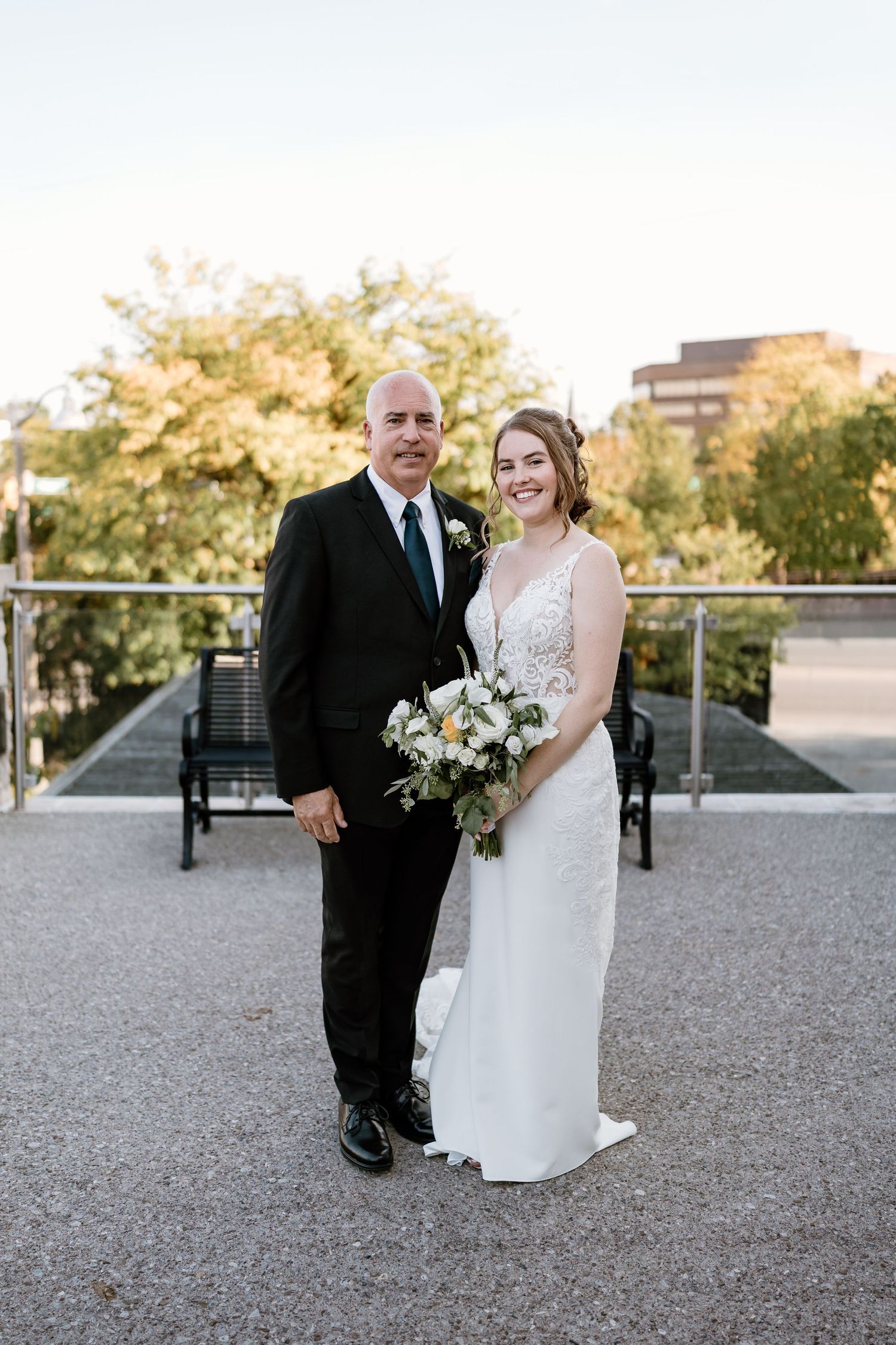 Elegant wedding portrait on modern terrace with autumn trees in background.