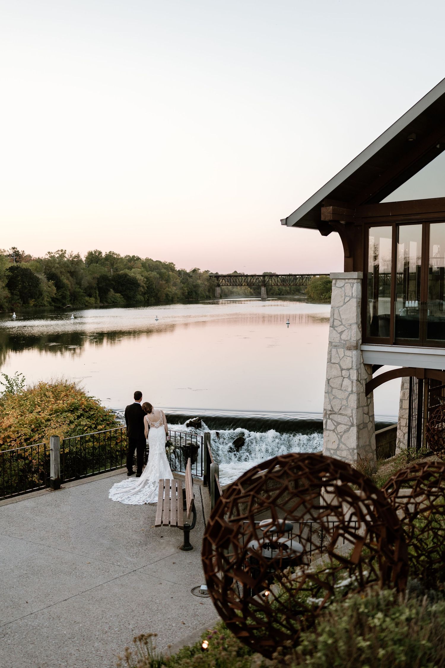 Scenic stone pavilion overlooking a tranquil lake at sunset.
