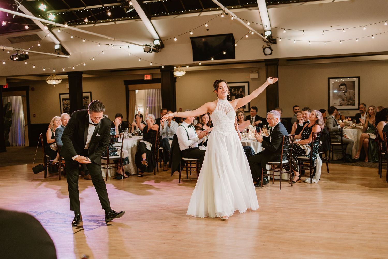 Couples dancing at wedding reception with guests seated around the dance floor.
