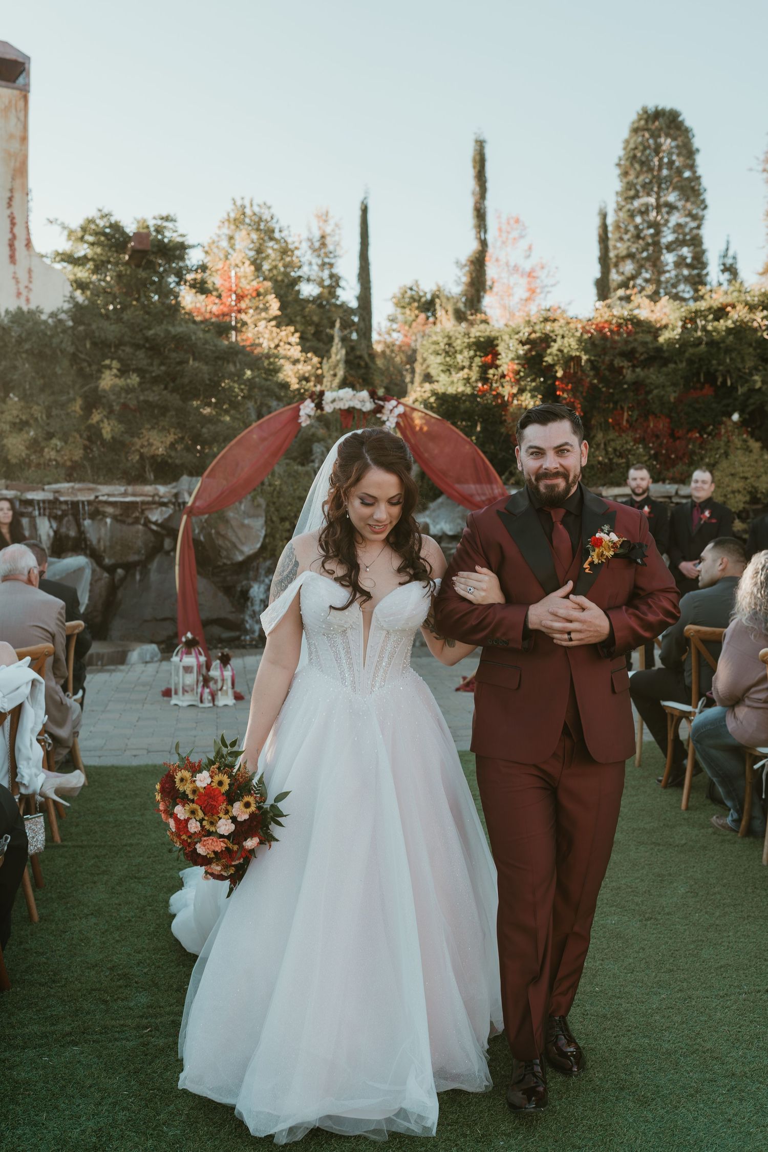 A couple walks together on a grassy lawn in reno nevada at a sunset wedding ceremony while guests look on.