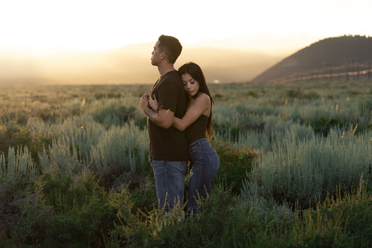 Couple sharing romantic embraces in a desert landscape during golden hour with sagebrush and mountains in background near mammoth lake, CA.