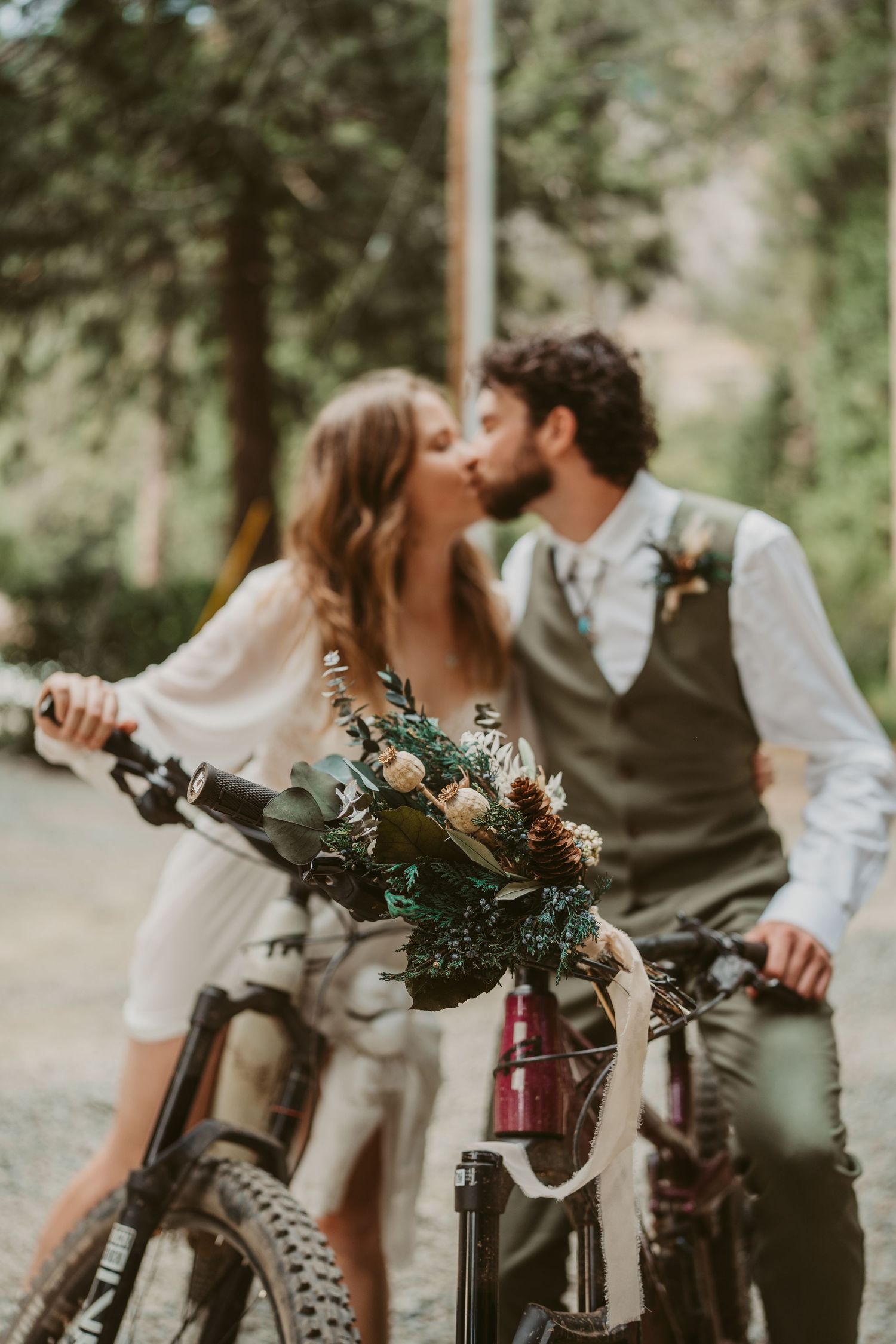 A romantic couple shares tender moments with mountain bicycles in a dreamy outdoor wedding portraits.