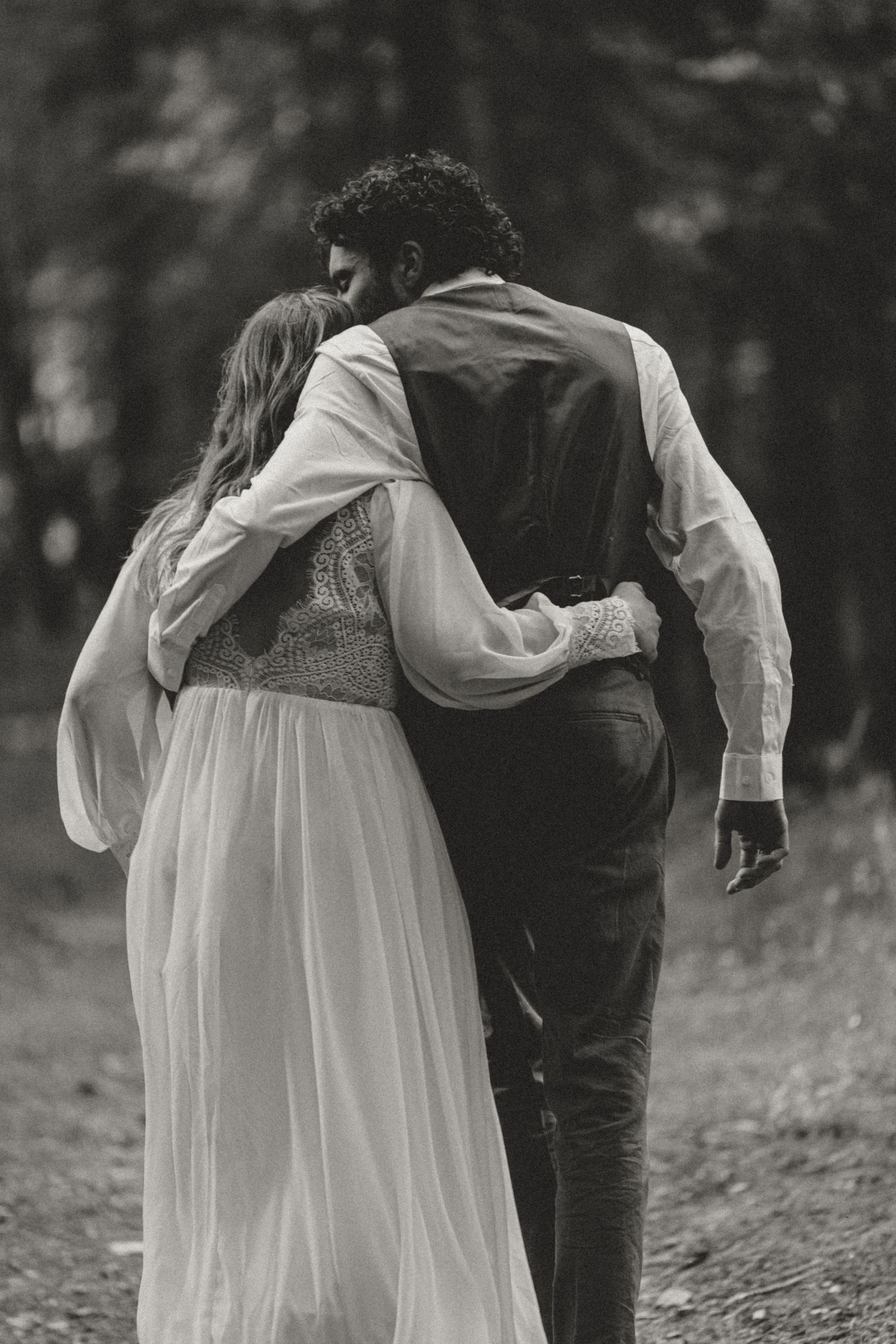 A romantic black and white photo series showing a couple walking together in a forest setting.