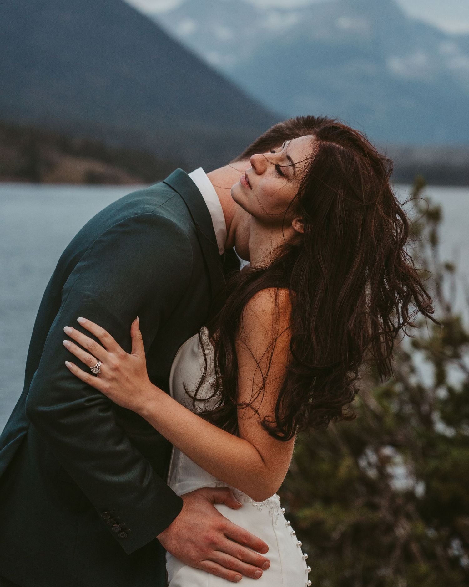A romantic couple embraces against a misty mountain backdrop during a wedding photoshoot.