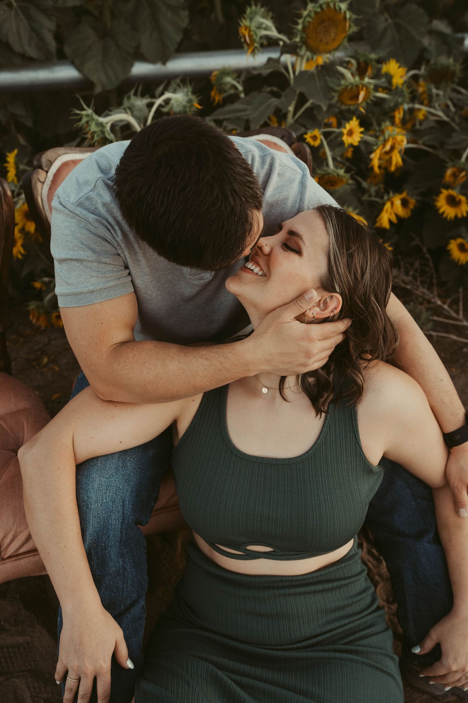 A romantic moment shared between a couple in a garden with blooming sunflowers in the background.