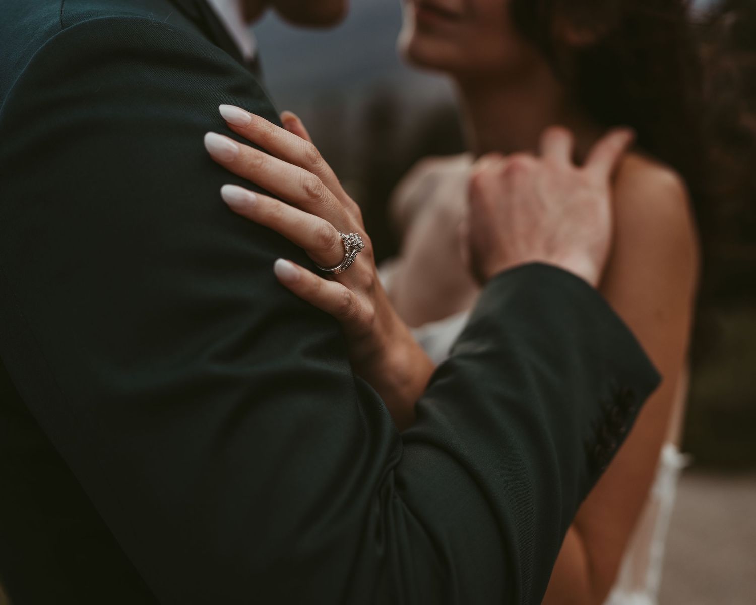 A couple sharing an intimate moment in wedding attire on a lake side scenic overlook.