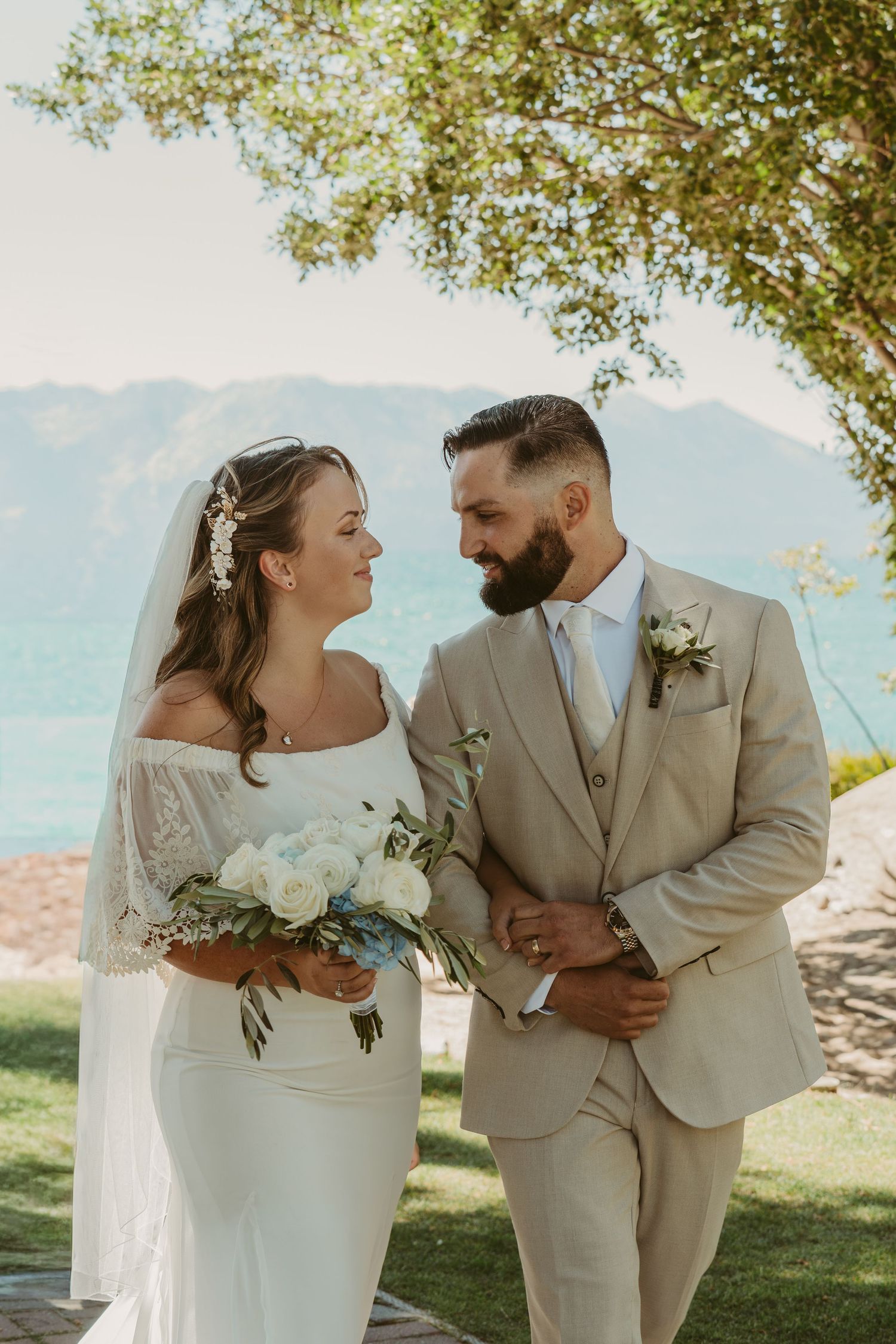 A joyful wedding couple shares intimate moments outdoors with mountains and trees in the background.