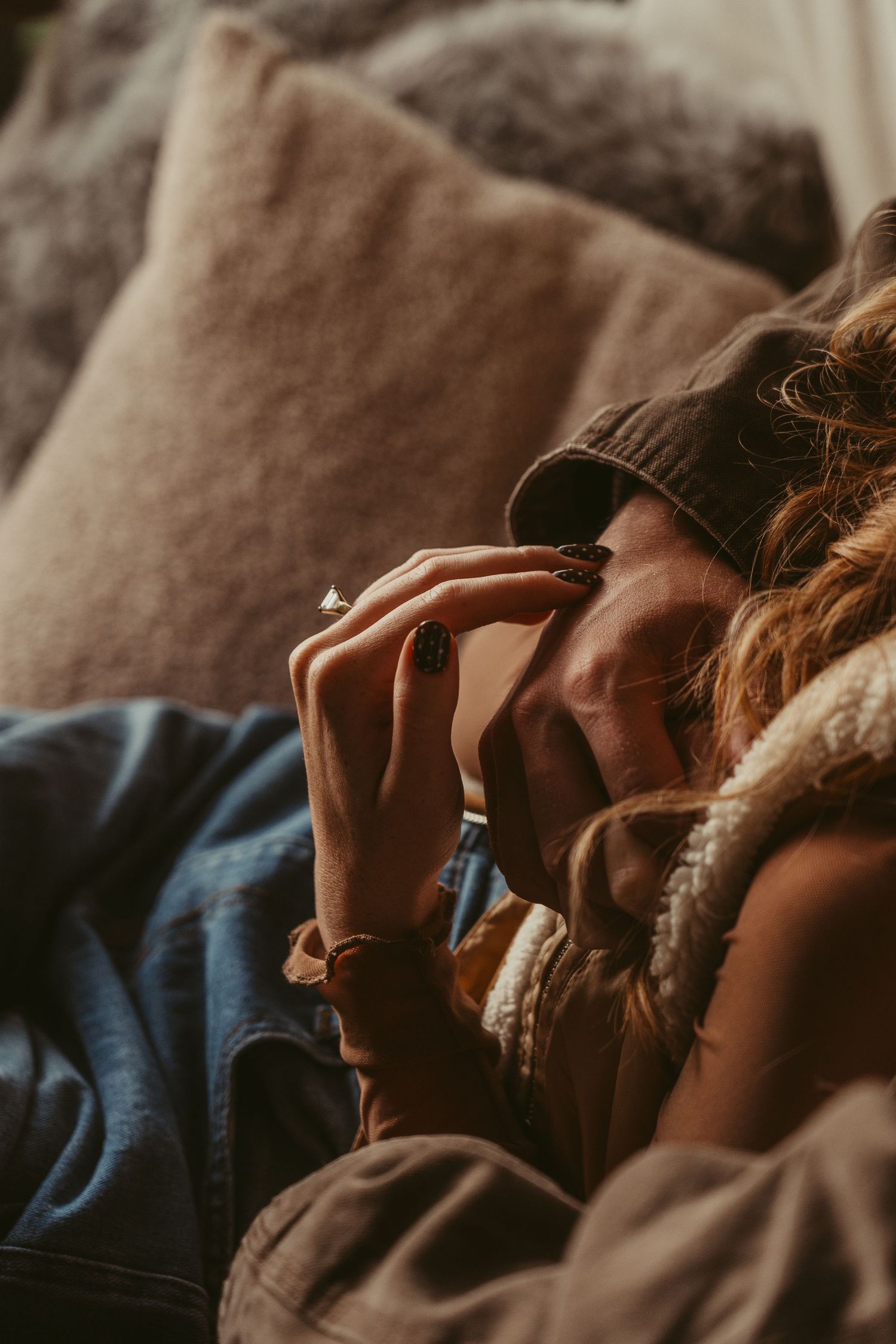 A person lies down while being comforted with gentle hand touches in a dimly lit, intimate setting.