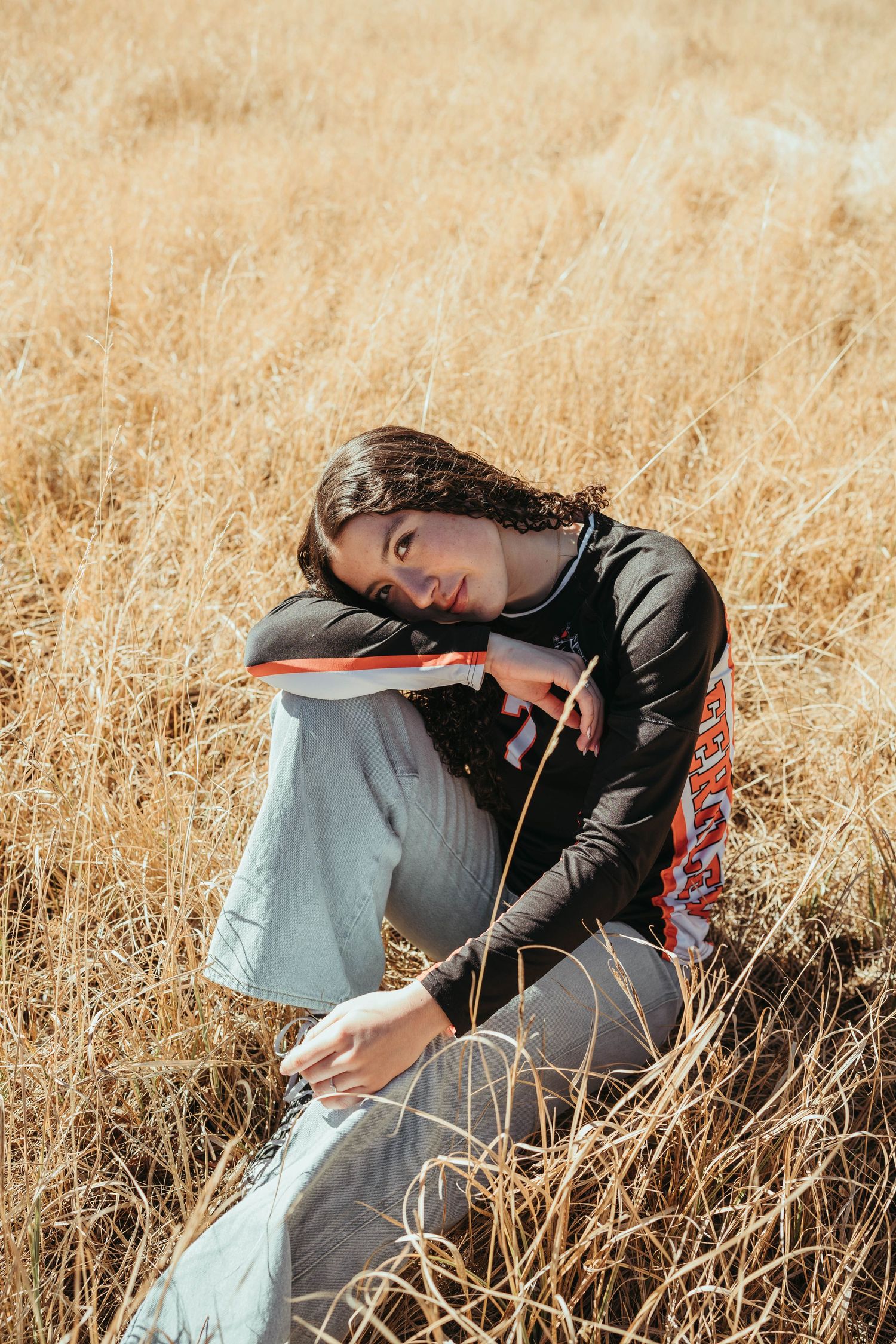 Person in black sports jersey lying in golden wheat field during autumn season.