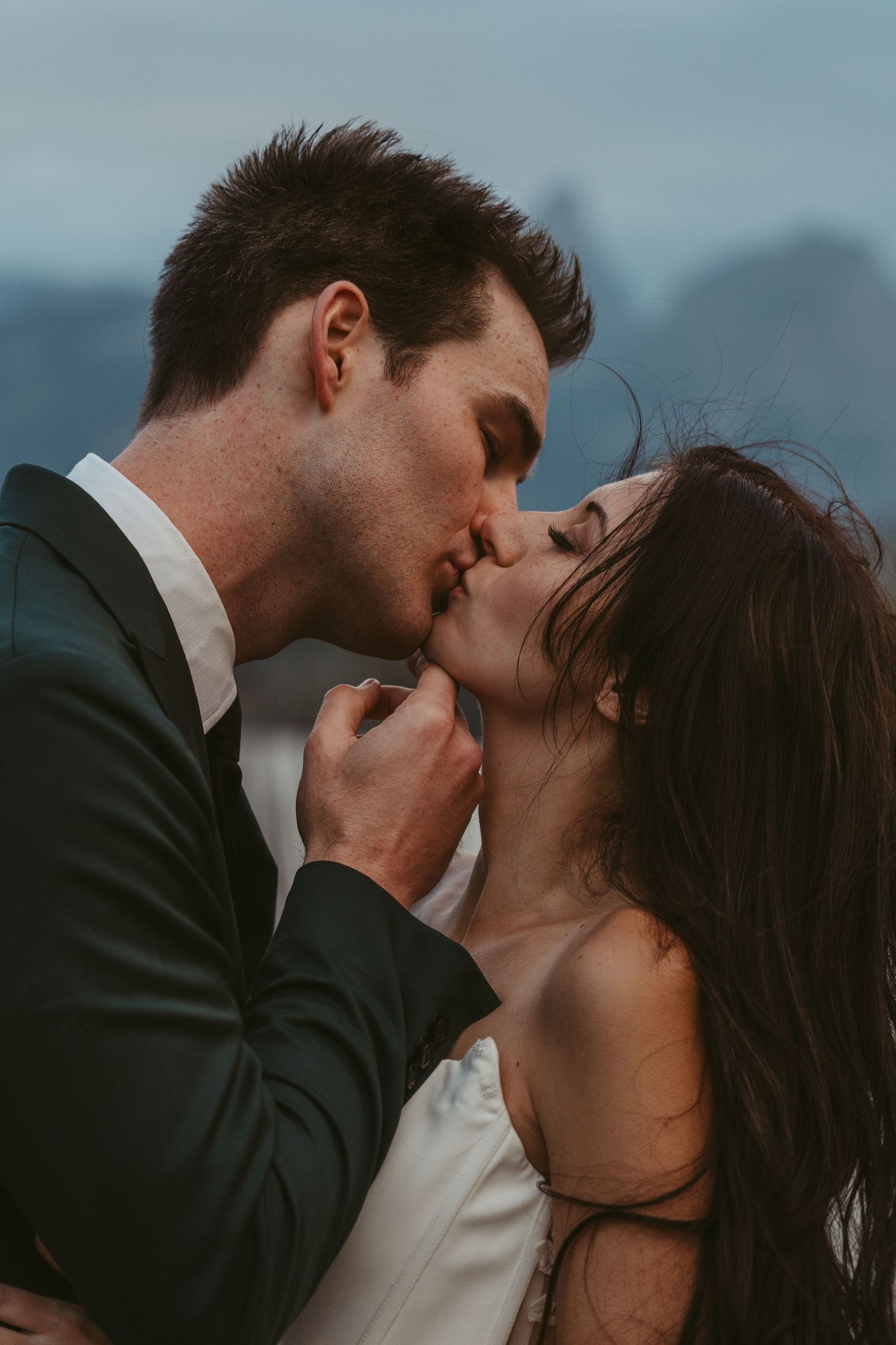 A romantic sequence of wedding photos showing a couple sharing an intimate kiss against a moody mountain backdrop.
