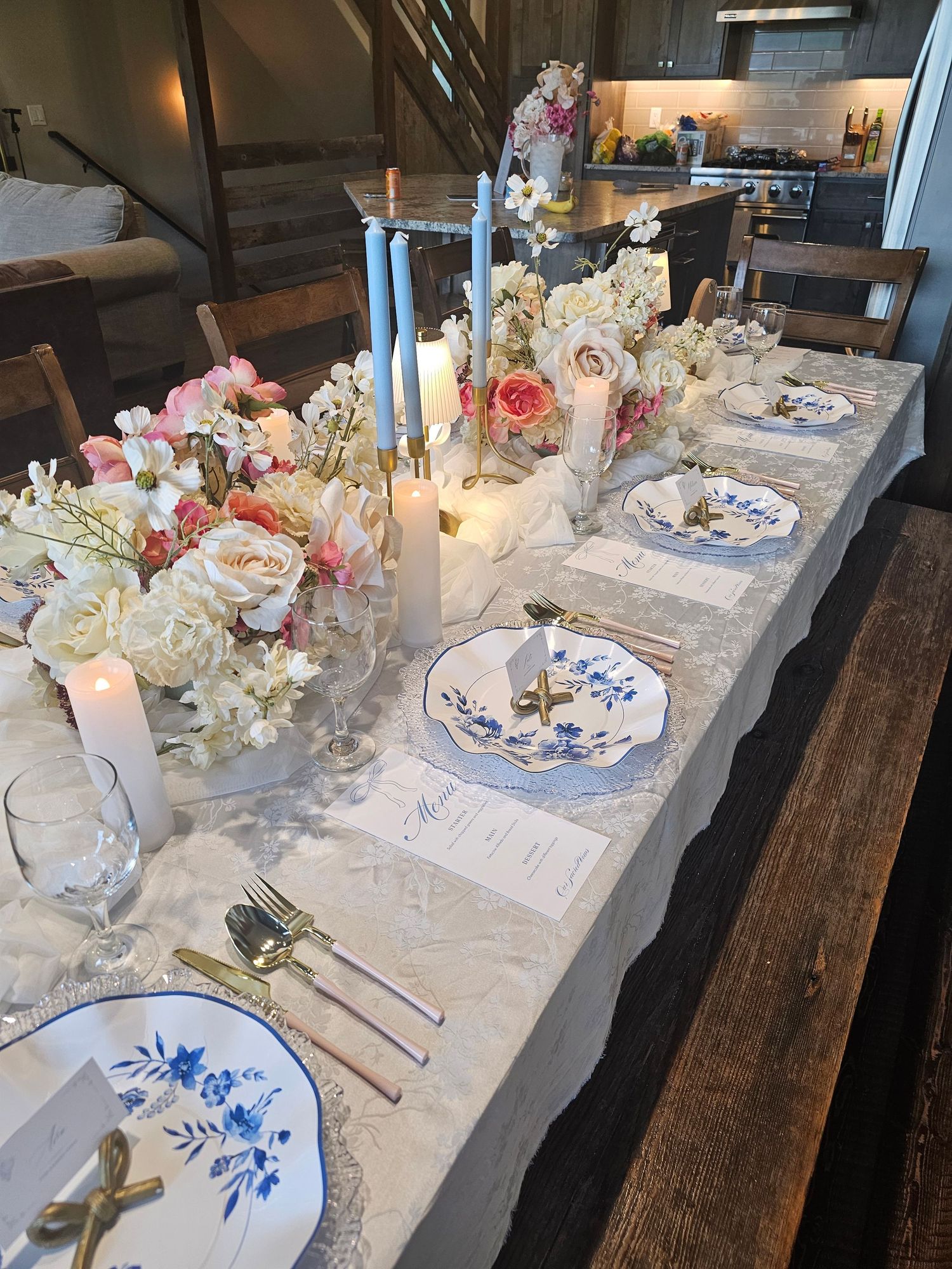 An elegant welcome dinner table setting with white linens, floral centerpieces, and blue and white china plates.