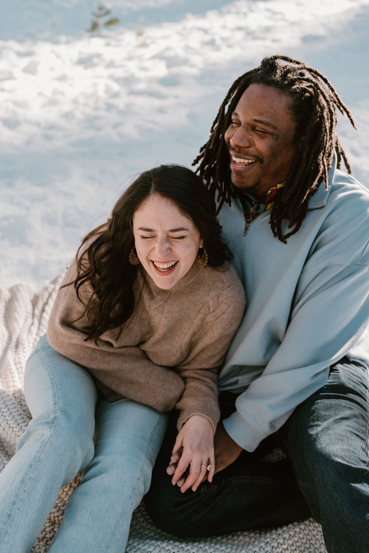 Couple sharing joyful moments while sitting together in the snow.