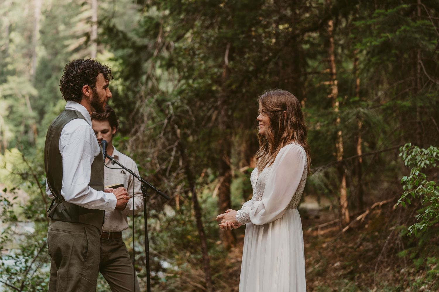 Couple in wedding attire shares romantic moments in a lush forest setting during their wedding ceremony.