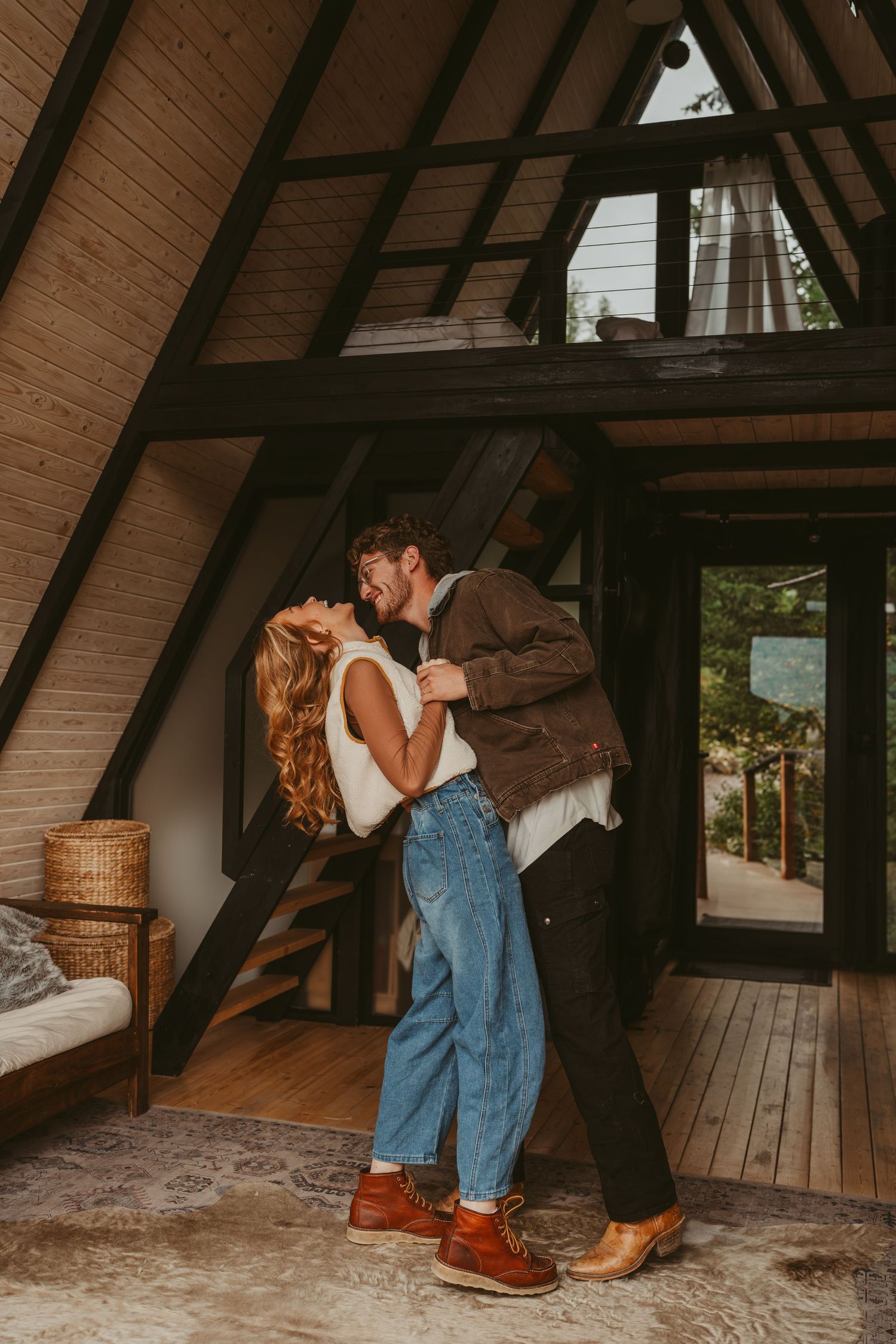 A romantic couple embraces in a cozy A-frame cabin with wooden beams and rustic decor.
