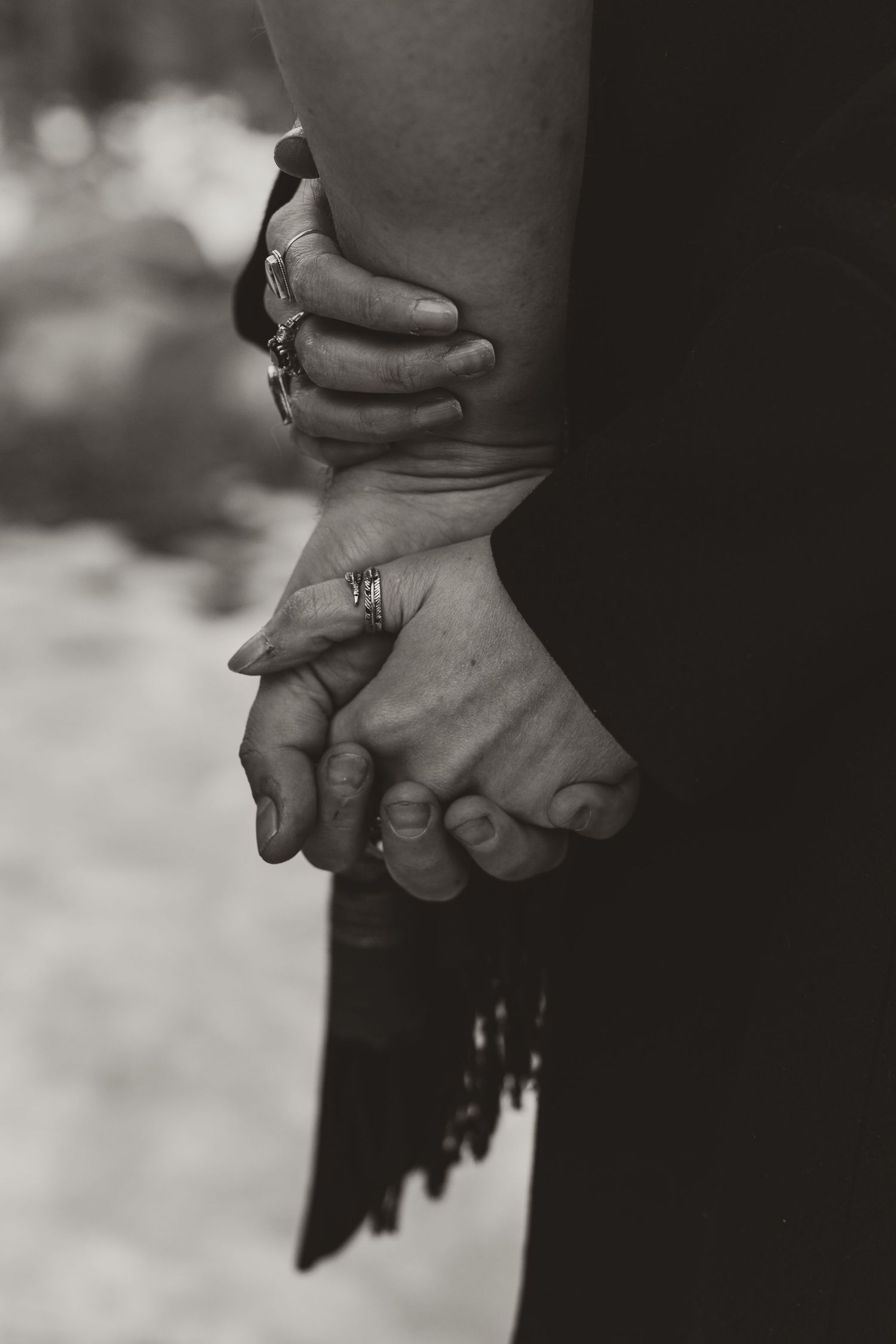 Black and white close-up photograph of two hands tenderly clasped together in an intimate moment.