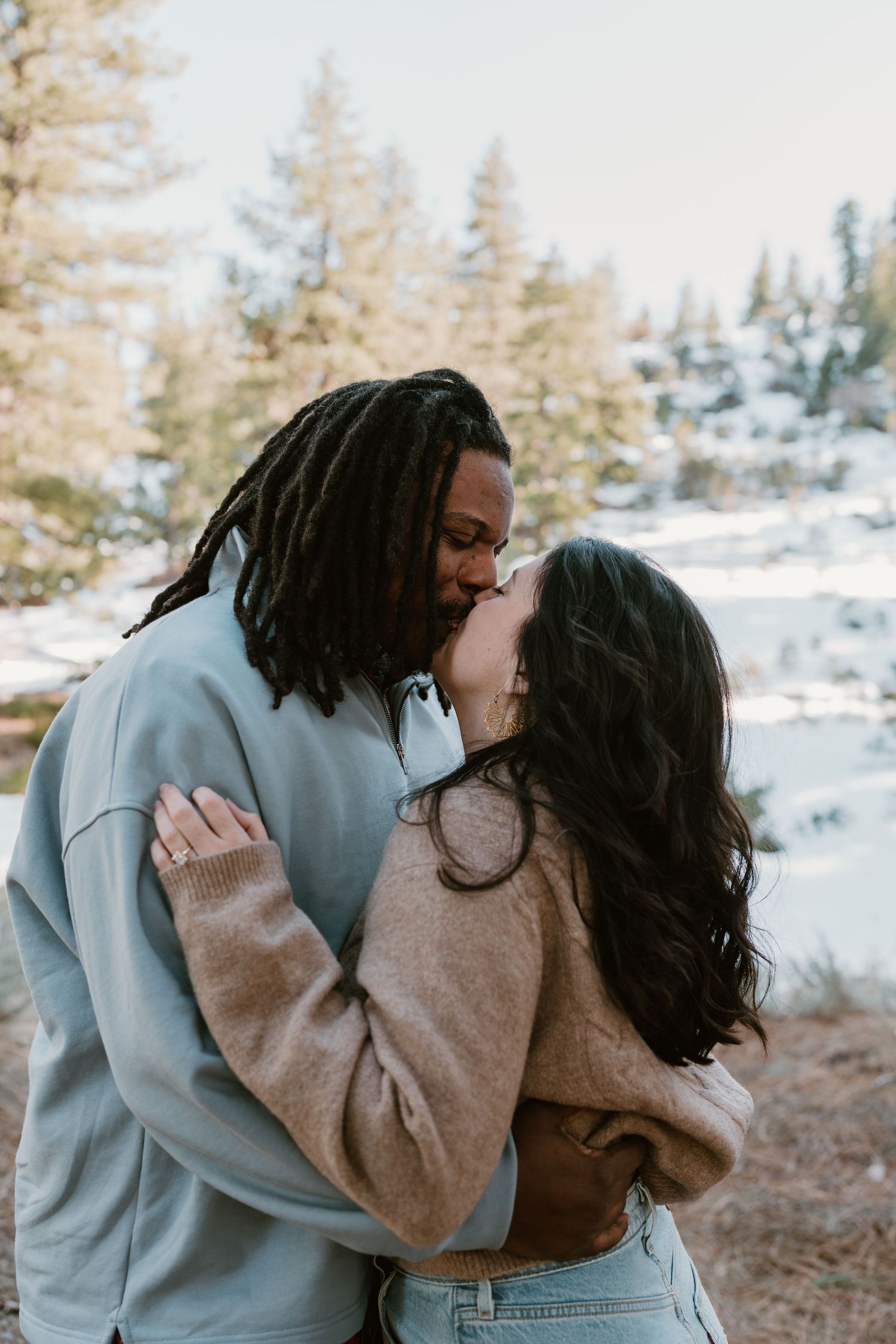 Romantic winter photoshoot in a snow-covered forest landscape.