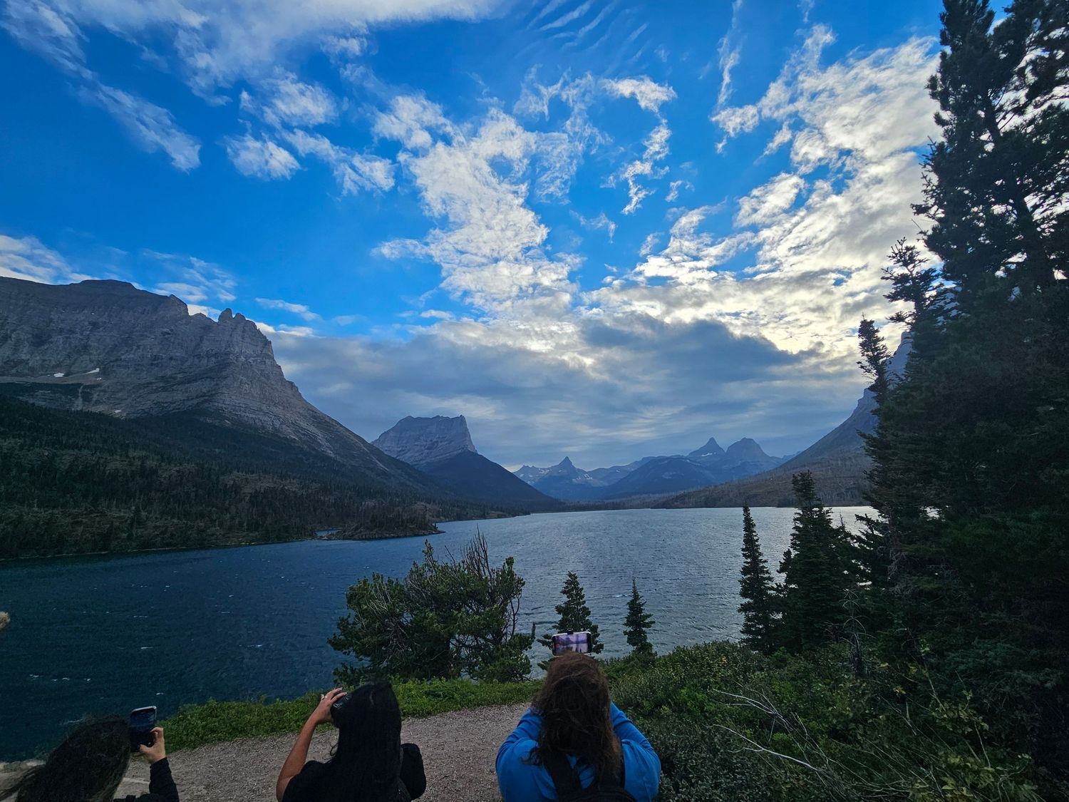 A panoramic view of Saint Mary Lake in Glacier National Park with snow-capped mountains and blue skies.