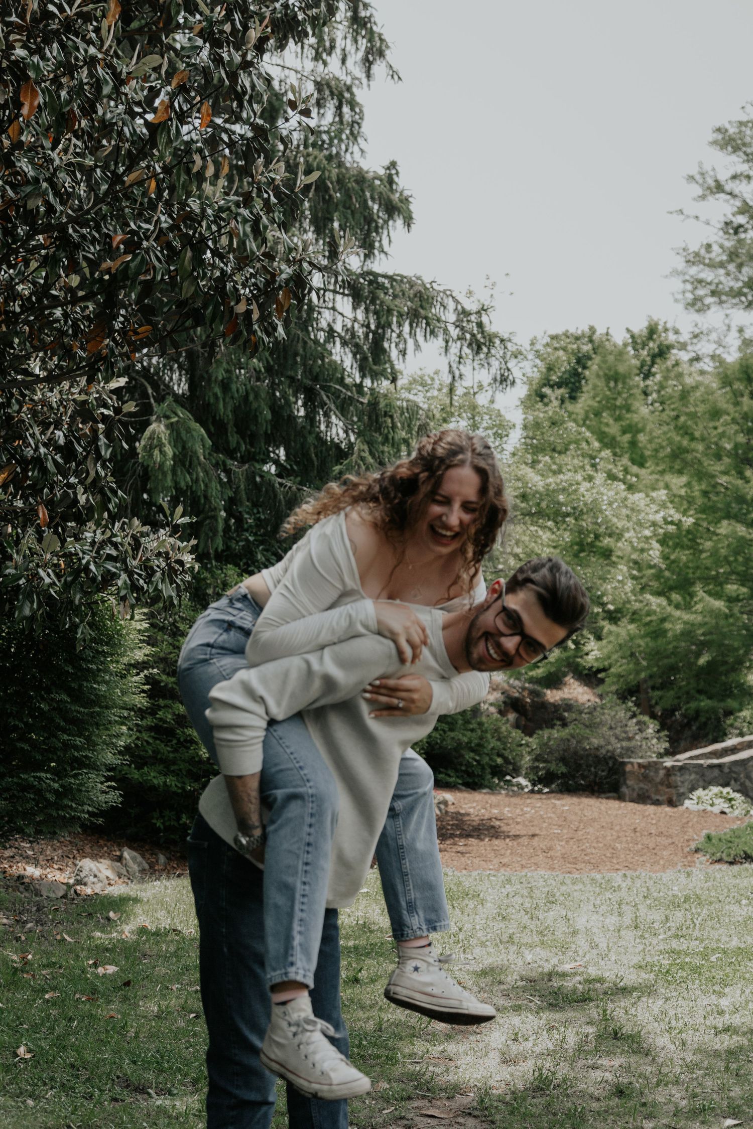 Laughing couple enjoying a piggyback ride in a lush green garden setting. rock quarry garden greenville sc