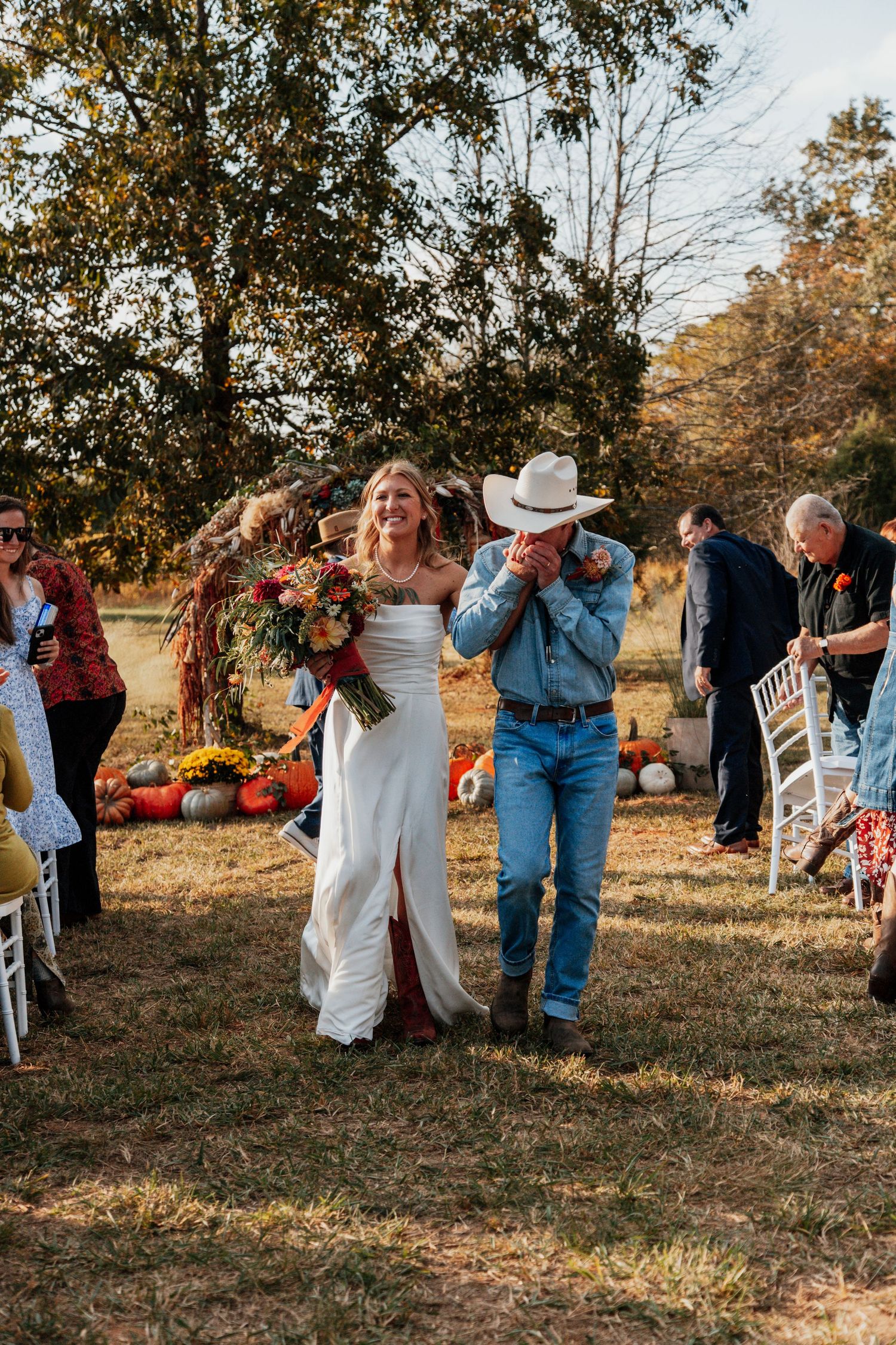Emotional father in cowboy hat kisses bride's hand while walking her down the aisle at an outdoor fall wedding. Preserve at Lakewood SC