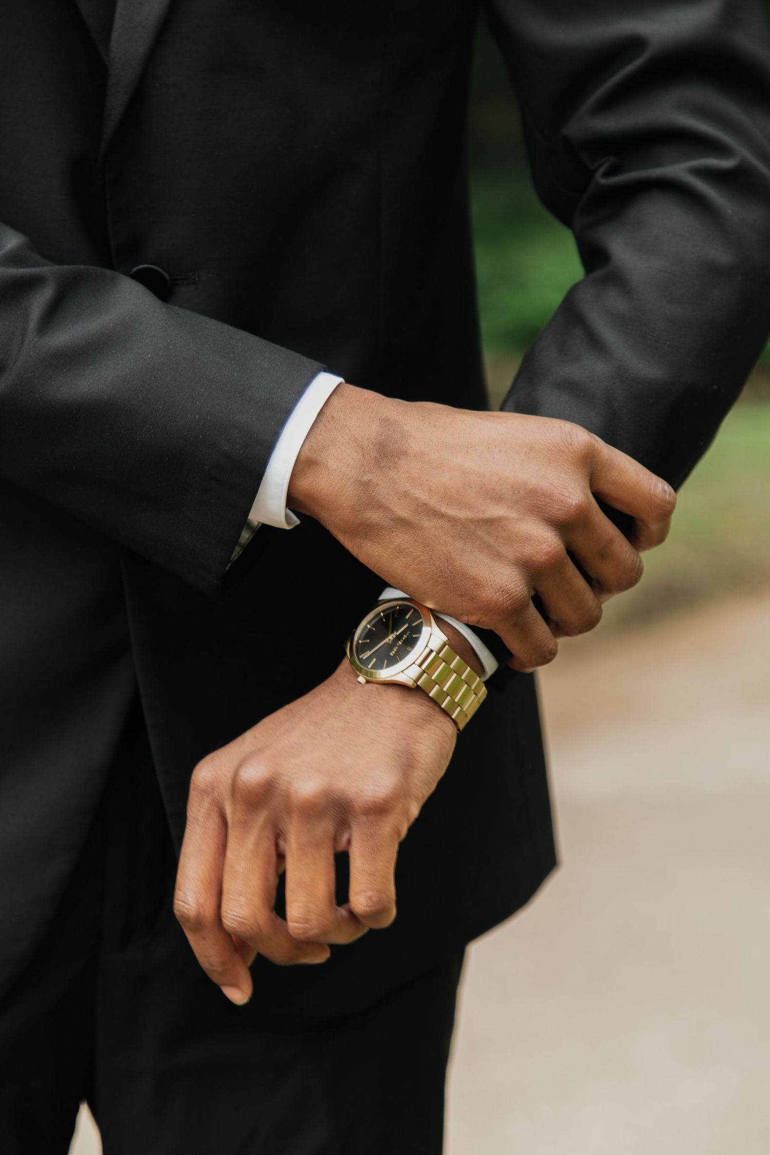 Groom adjusting gold watch on wrist wearing a black suit on wedding day.  falls park greenville sc