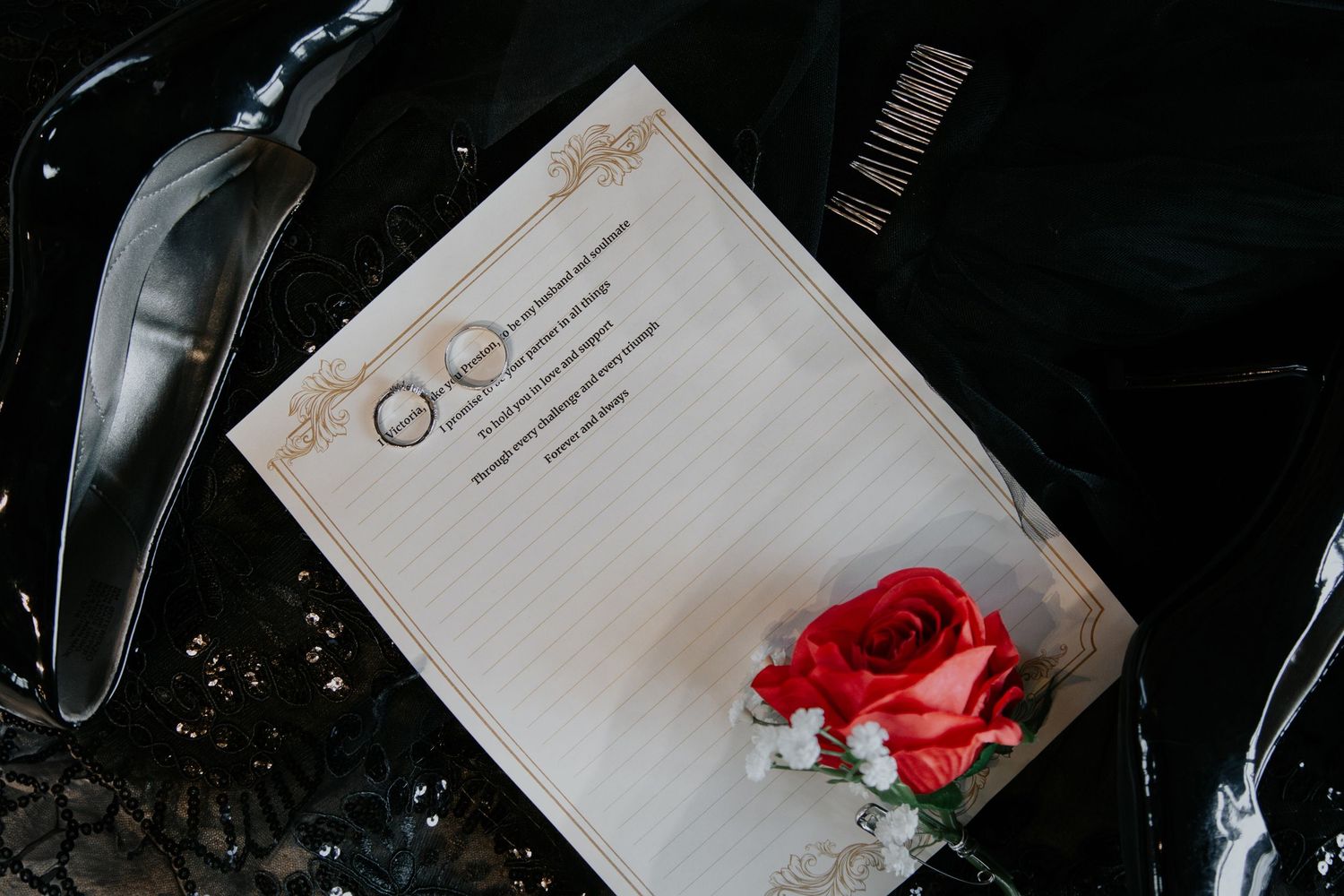 A wedding program with gold border design and a red rose boutonniere on a dark surface.