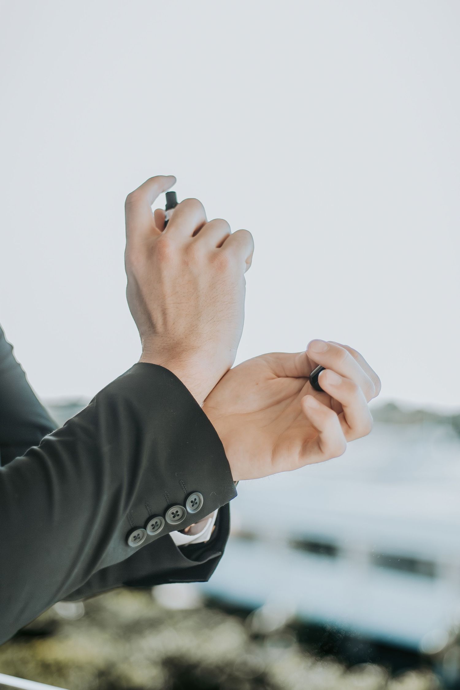 Groom in dark suit adjusts cufflinks outdoors before wedding ceremony. - riviera maya resort (cancun, Mexico)