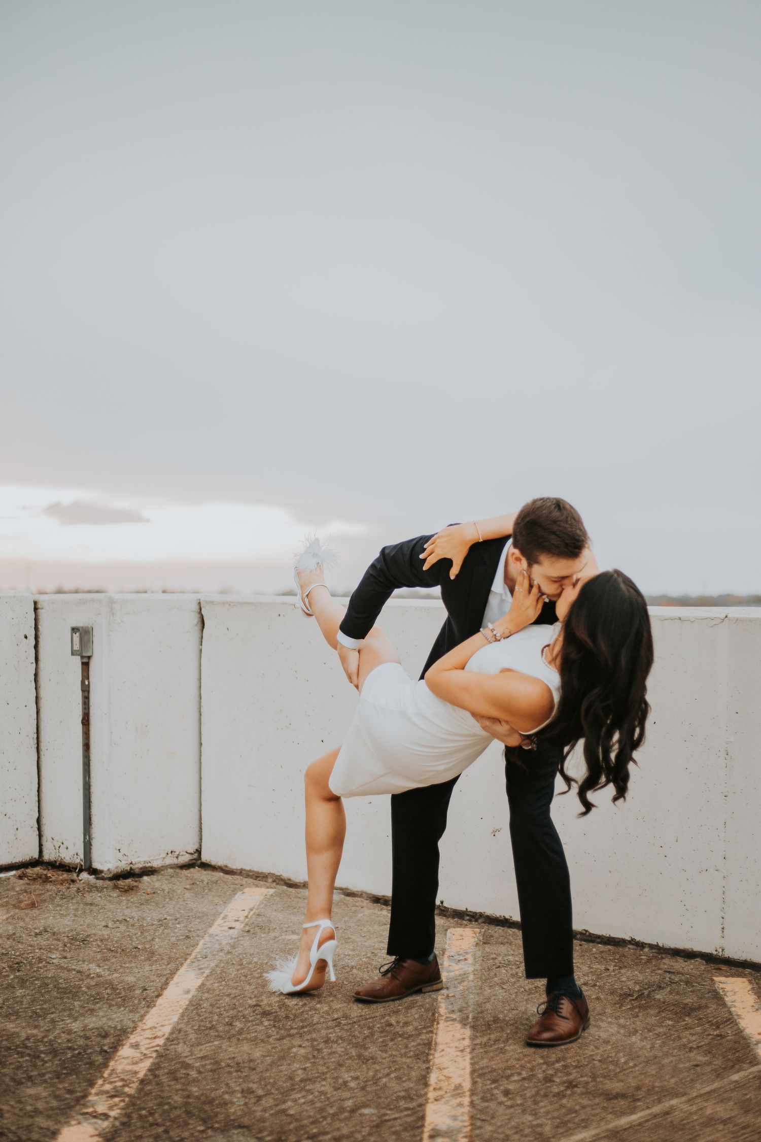 Man dipping woman in a romantic kiss on a rooftop at dusk, woman in white dress. greenville sc
