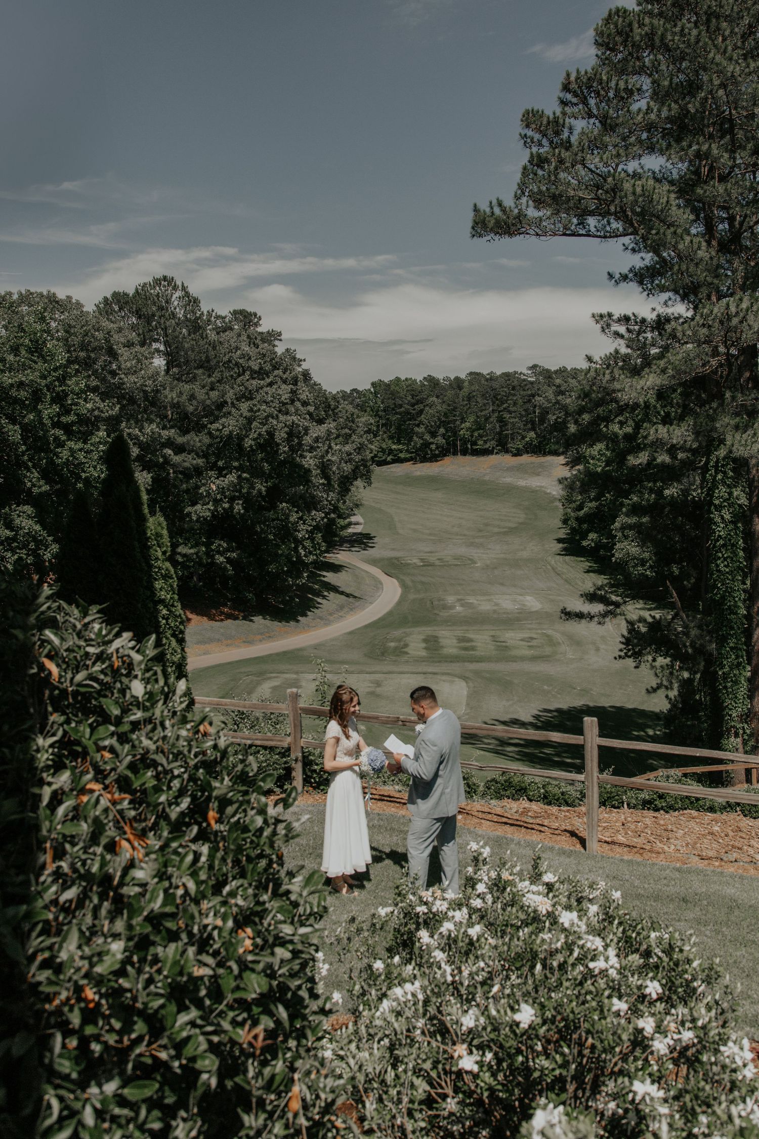 Bride and groom exchanging vows outdoors overlooking scenic golf course surrounded by trees. keowee key country club salem sc