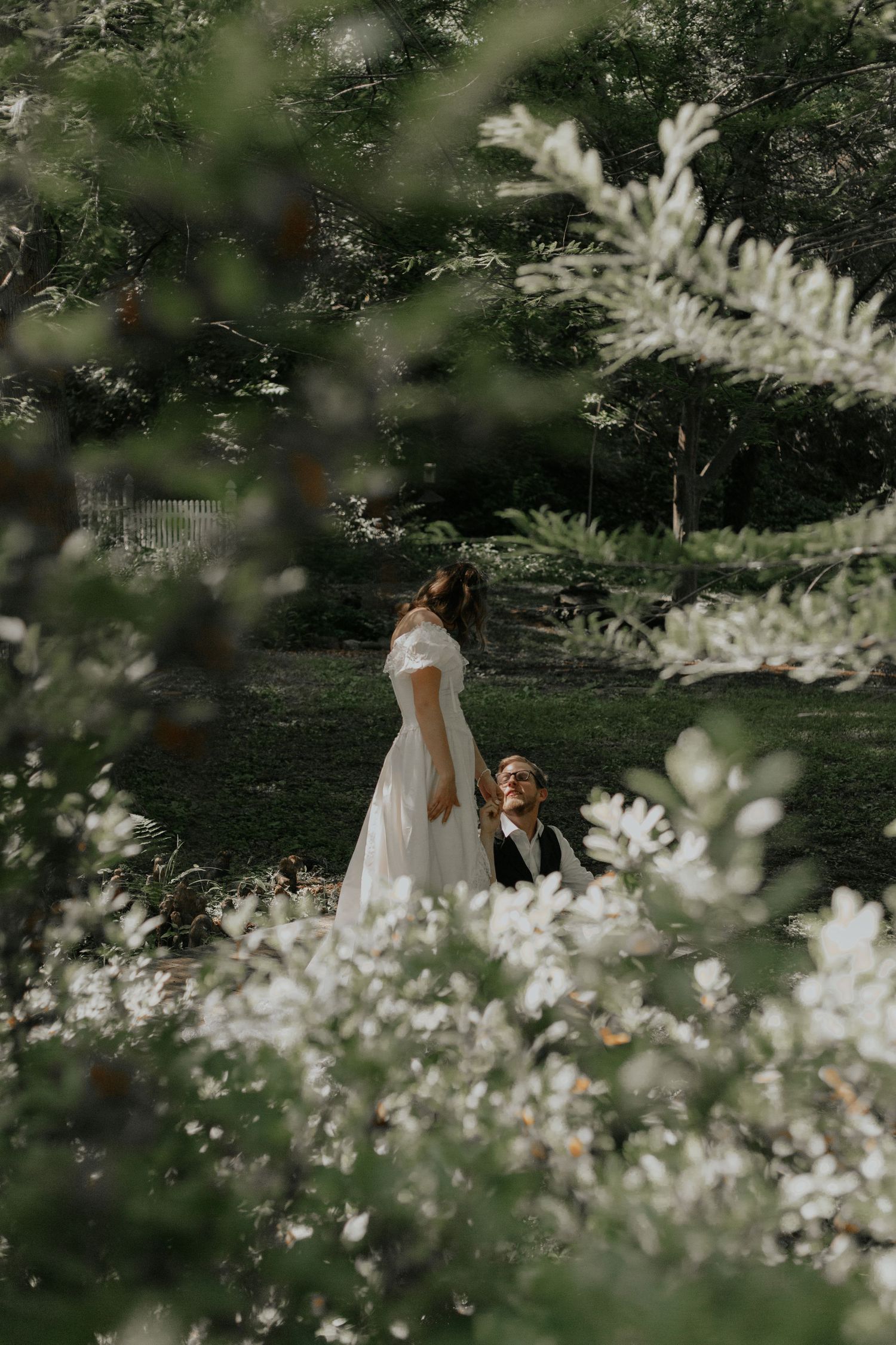 Bride and groom standing in a lush garden framed by white flowering branches in soft natural light. kilgore lewis house greenville sc