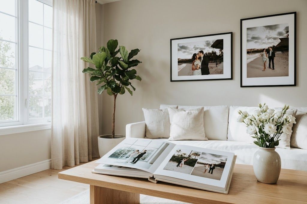 Bright living room with white sofa, photo album on wood coffee table, framed wedding photos, and a fiddle leaf fig plant.