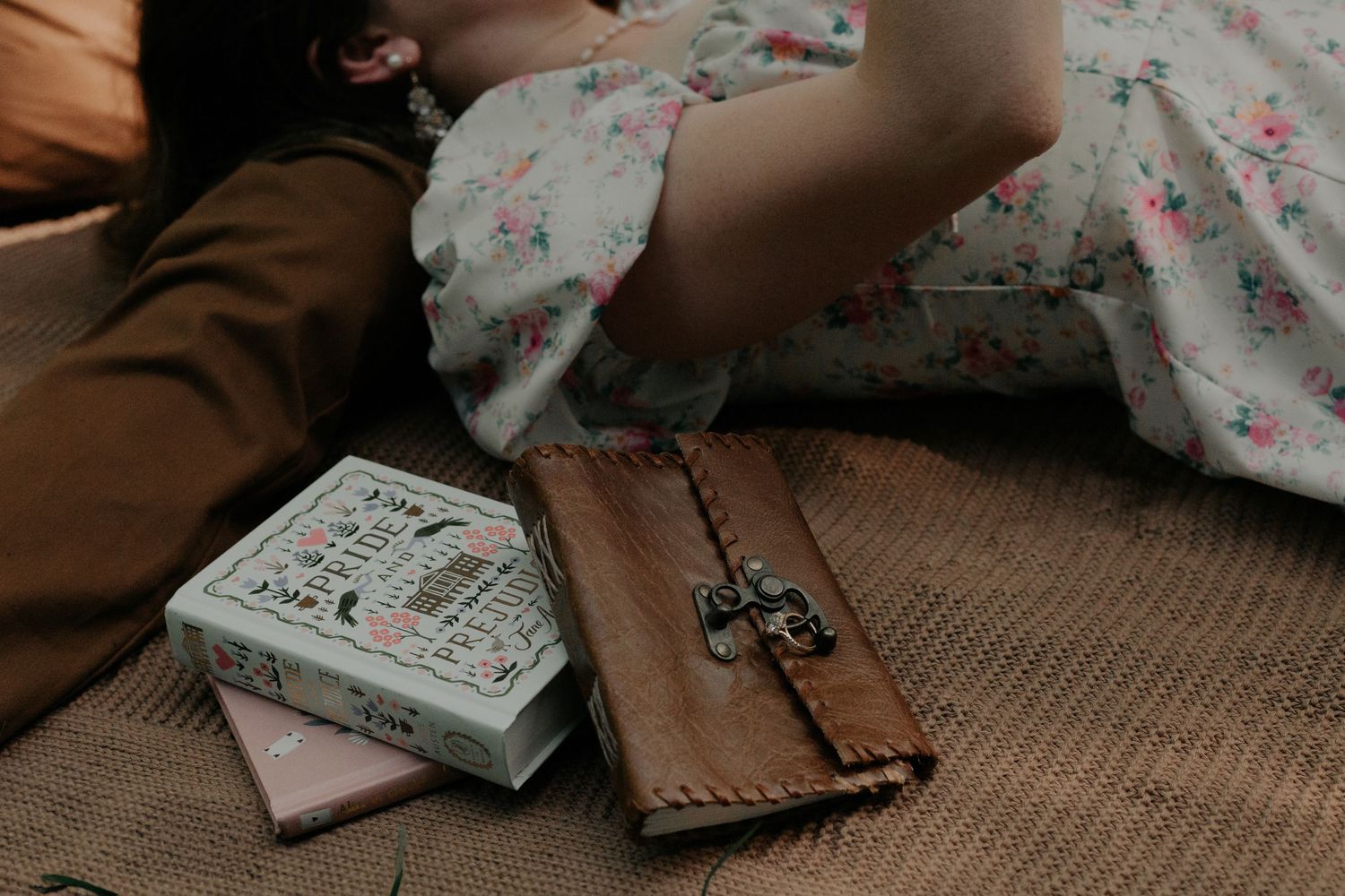 Couple relaxing on a blanket with a vintage leather journal and decorative box during outdoor picnic.
