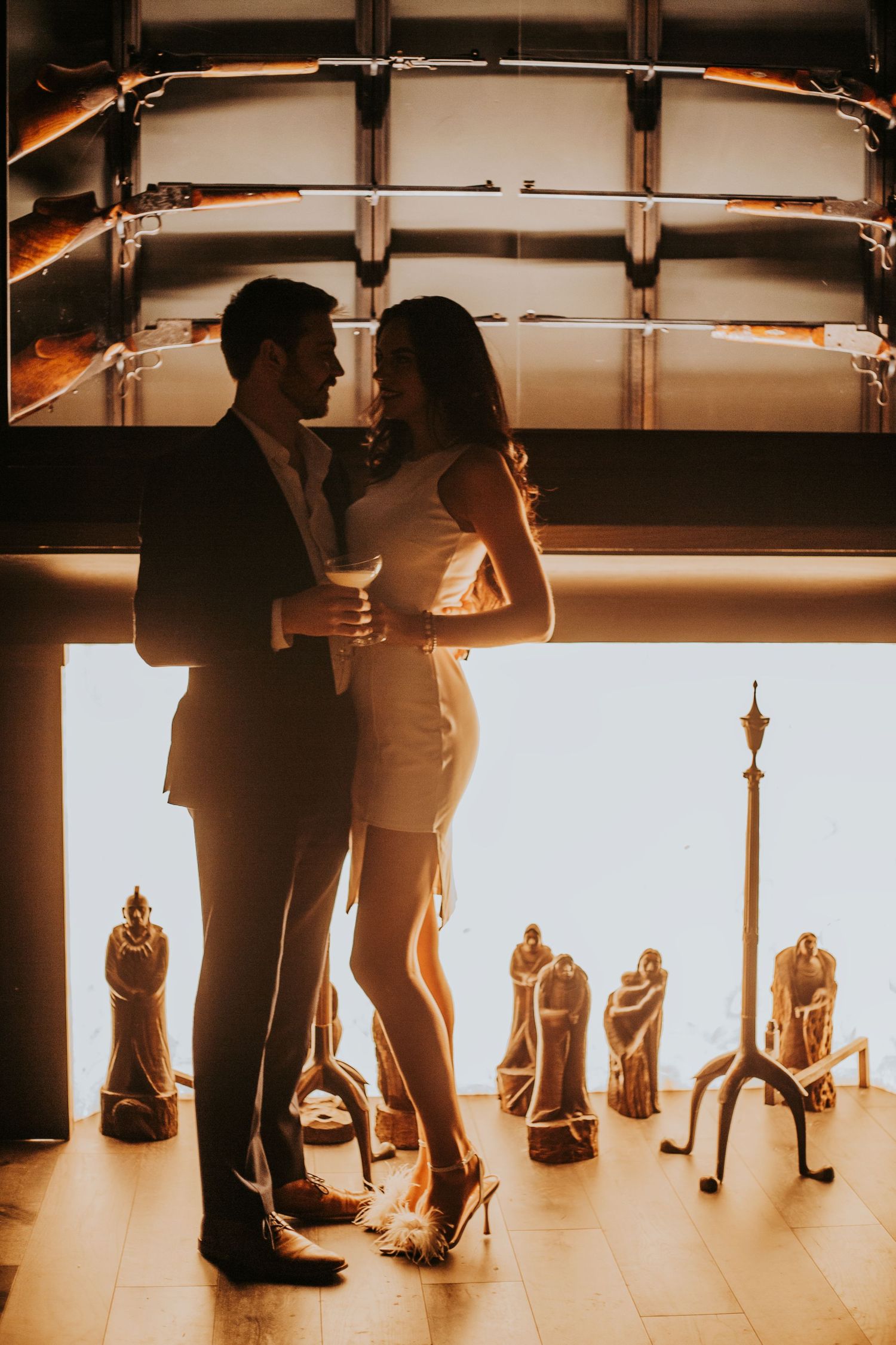 Elegant couple in formal attire sharing a romantic moment in a warmly lit venue with golden decor.