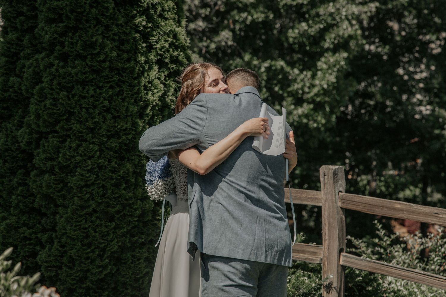 Bride and groom share emotional first look hug outdoors near wooden fence. keowee key country club salem sc