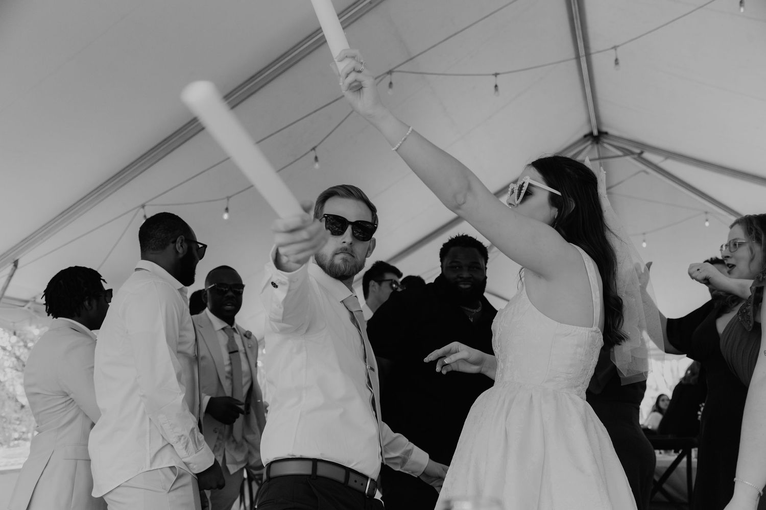 Black and white photo of wedding guests dancing and celebrating under a white tent at reception. Viewpoint at Buckhorn Creek Greenville SC.