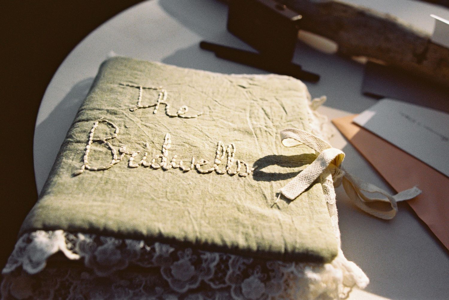 Elegant embroidered bridesmaid book with lace trim on a white plate at a wedding reception.
Big Sur Film Photography Wedding