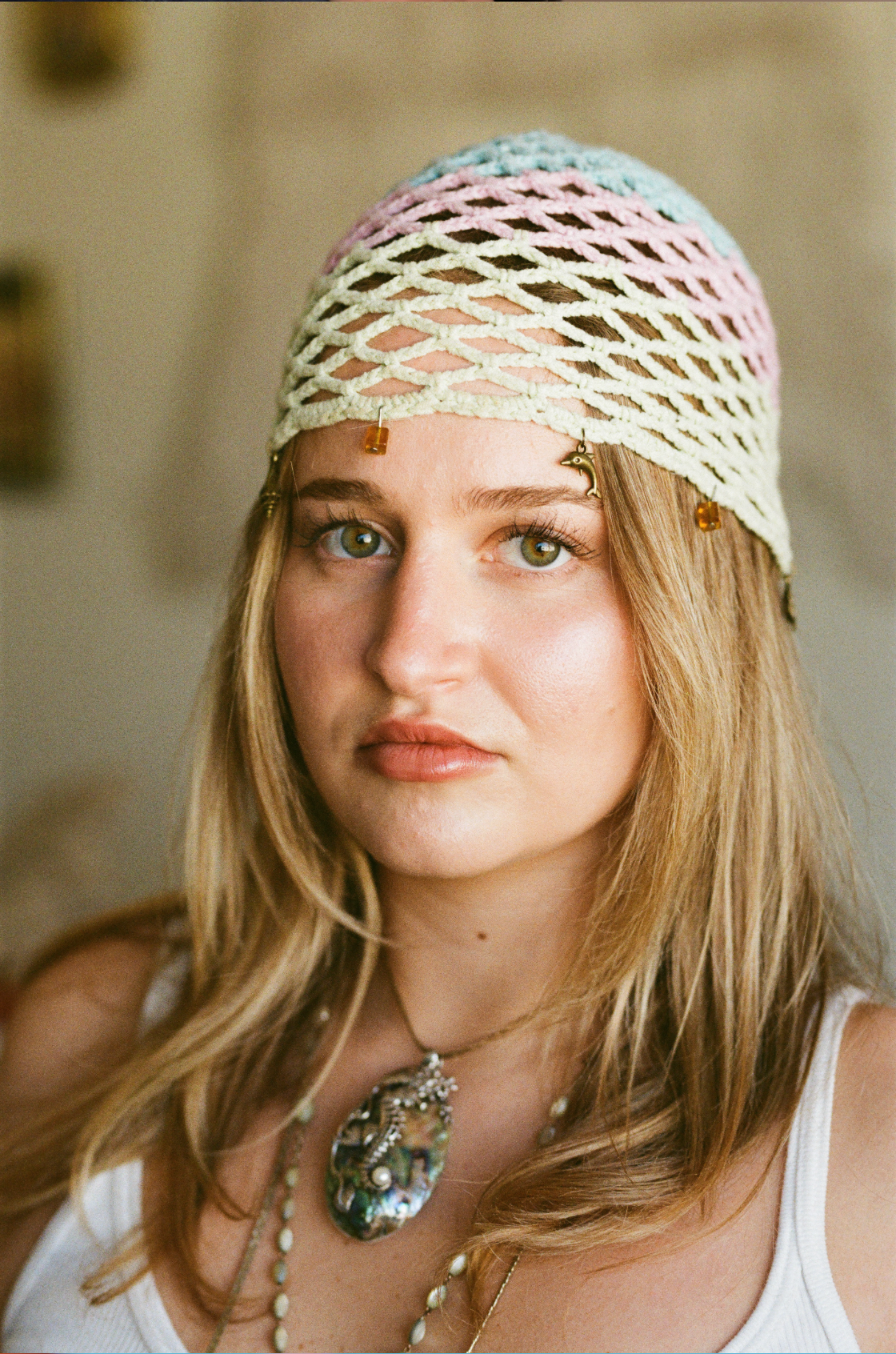 Young blonde woman wearing colorful macrame headband and statement necklace in film photo.
