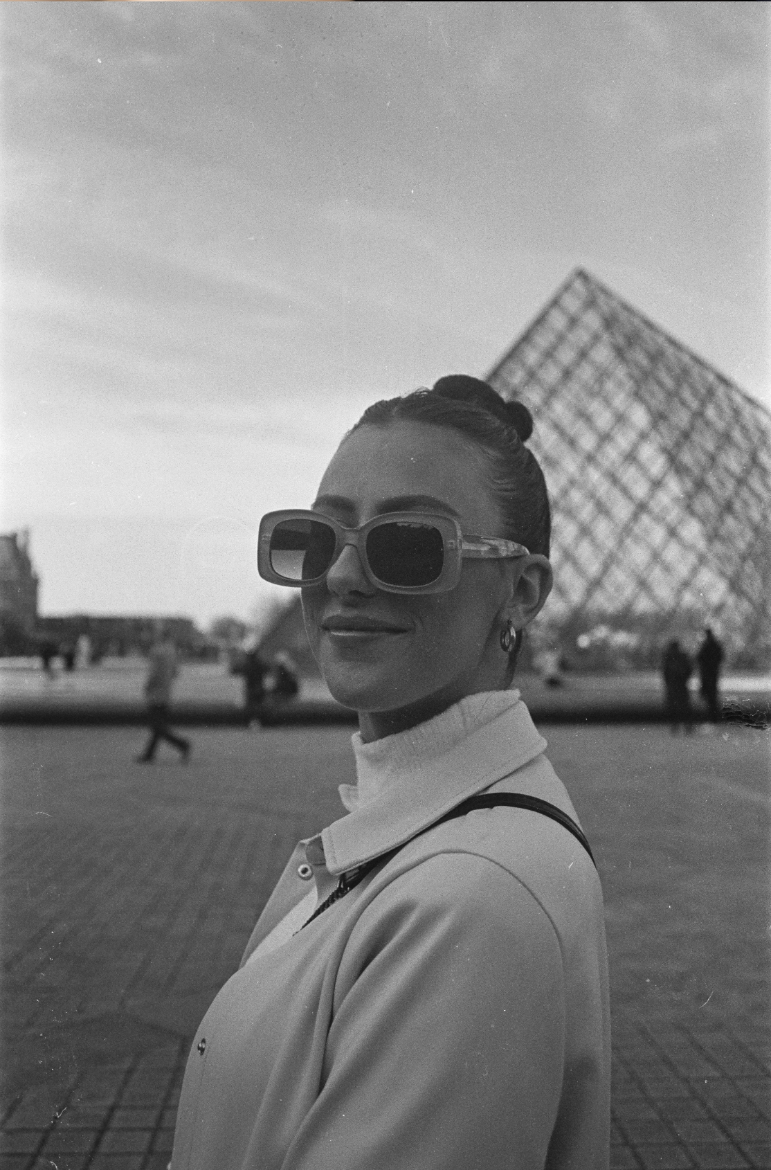 Stylish woman wearing oversized sunglasses in black and white photo at the Louvre Paris.