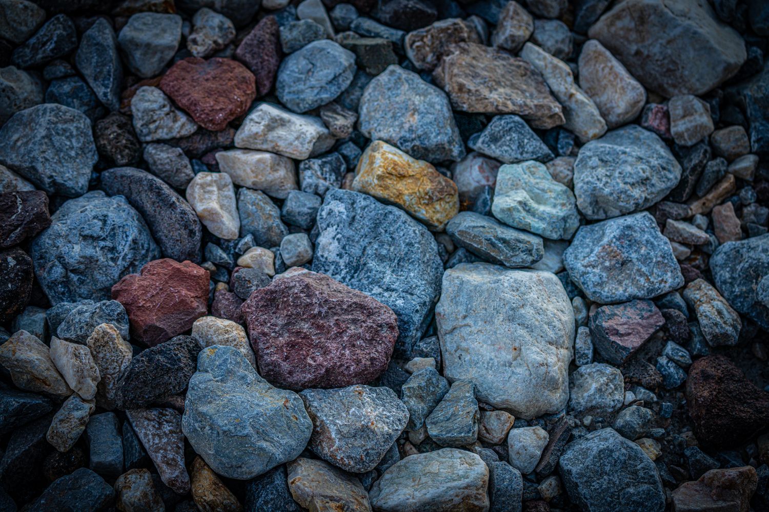 Close-up of colorful mixed rocks and stones in shades of blue, gray, red, and yellow.