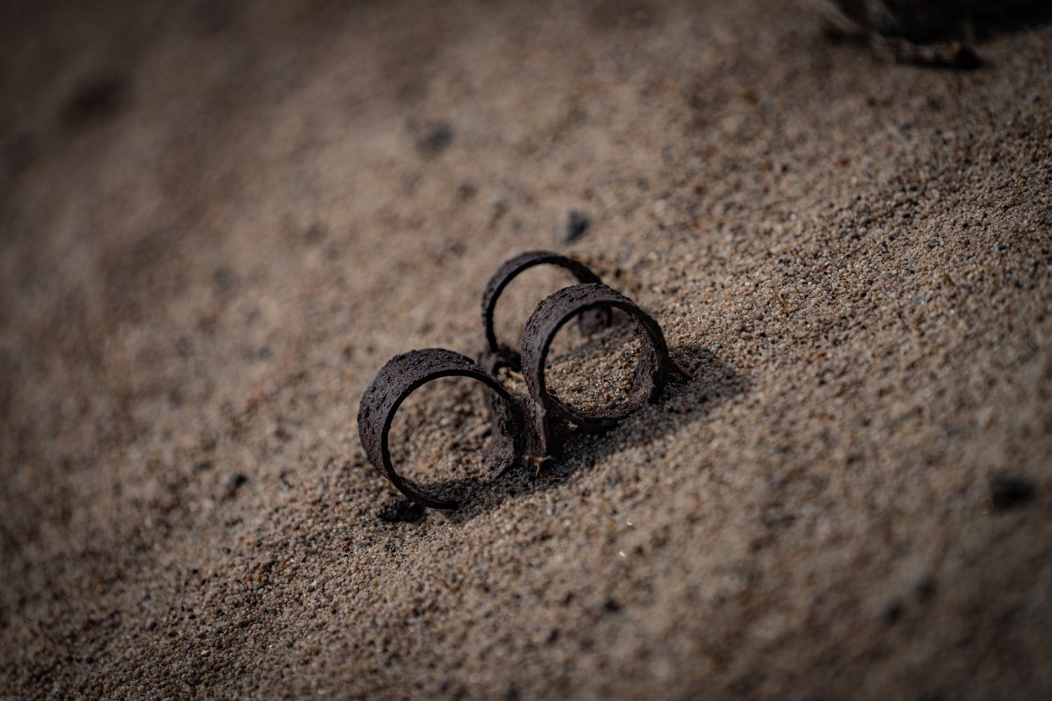 Two rusty metal rings partially buried in desert sand with shallow depth of field.